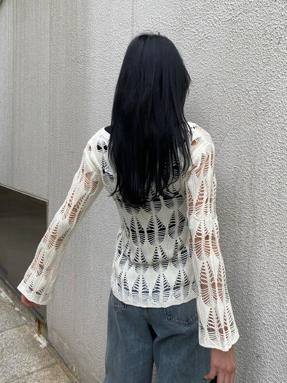 ブラック系のハンドバッグ、ブラック系のサンダル、ブルー系のデニムパンツを着用したレディースの春コーディネートの7枚目の写真