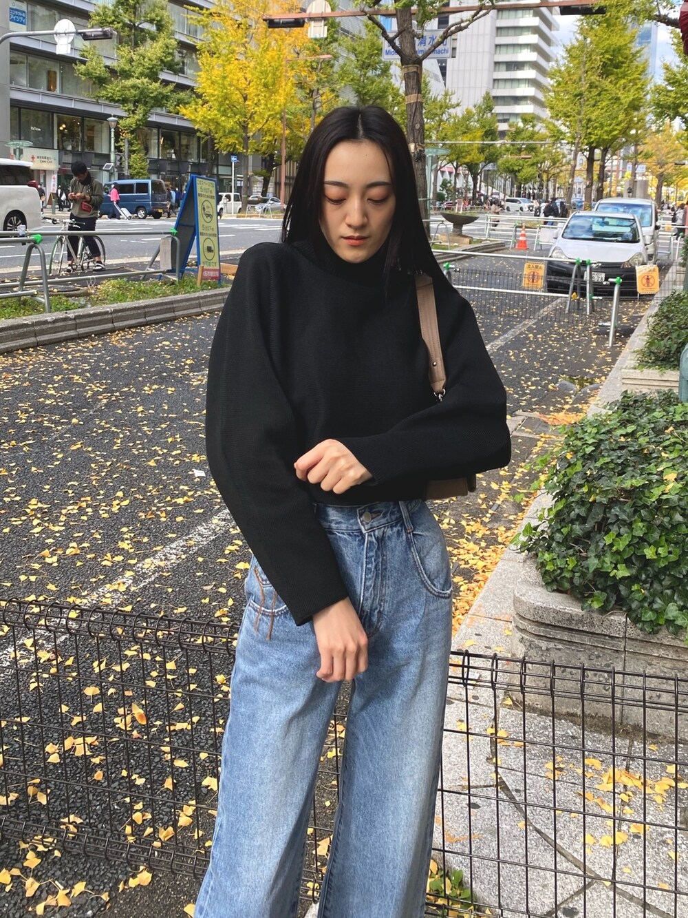 ブルー系のデニムパンツ、ブラック系のブーツ、ブラウン系のハンドバッグを着用したレディースの秋コーディネートの4枚目の写真