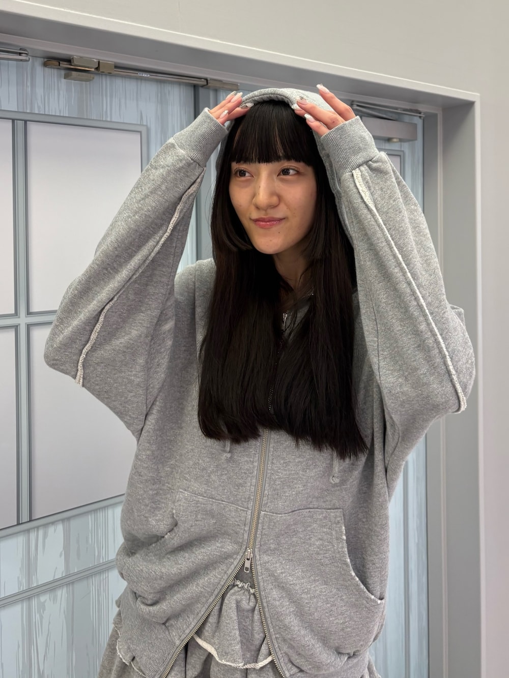 グレー系のスカート、グレー系のパーカー、ブラック系のブーツを着用したレディースの秋コーディネートの7枚目の写真