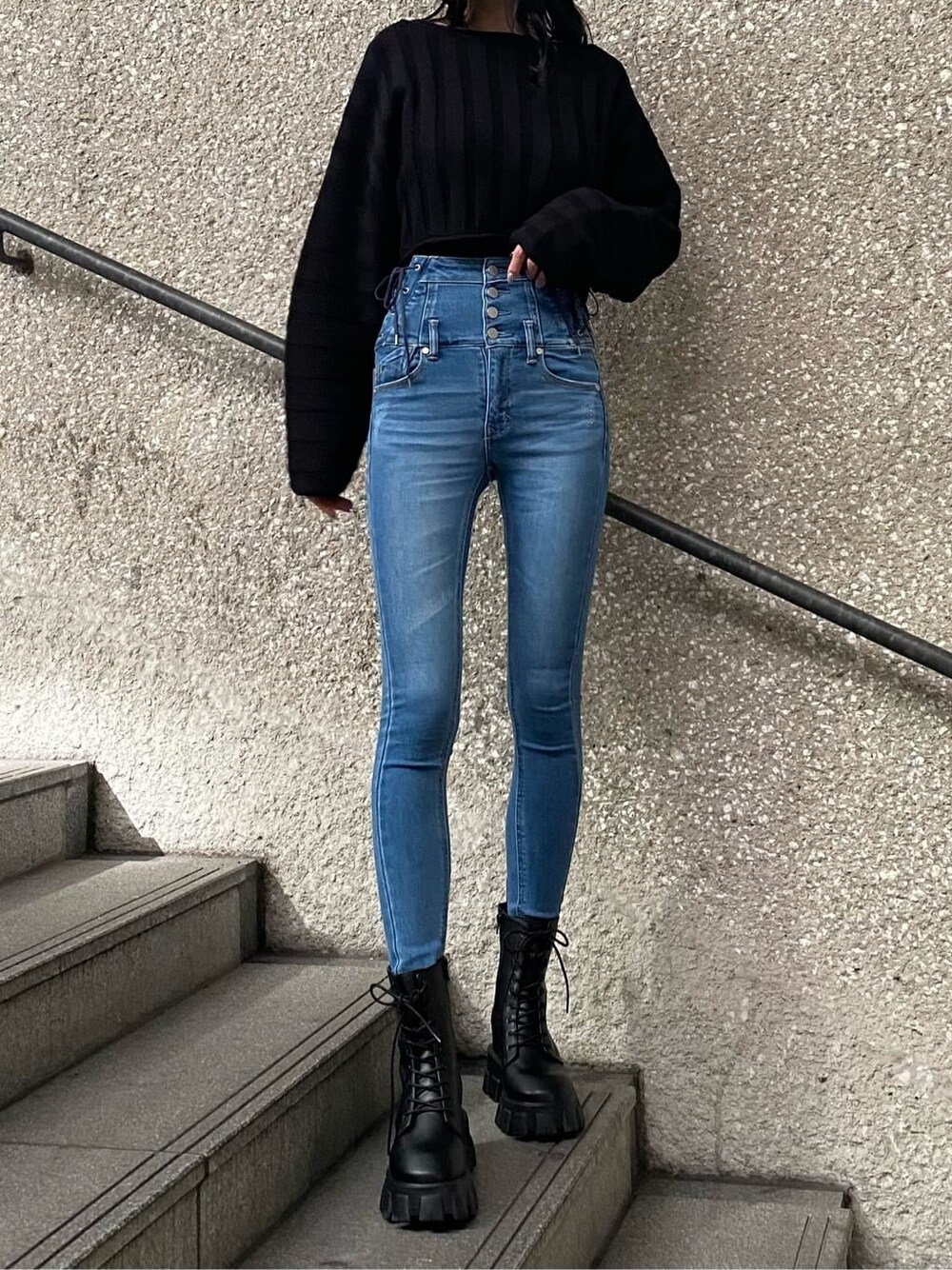 ブルー系のデニムパンツ、ブラック系のニット/セーター、ブラック系のブーツを着用したレディースの冬コーディネートの3枚目の写真