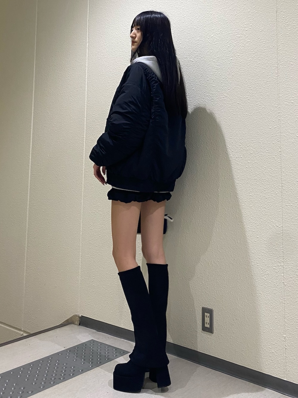 グレー系のパーカー、ブラック系のブルゾン、ブルー系のハンドバッグを着用したレディースの秋コーディネートの3枚目の写真