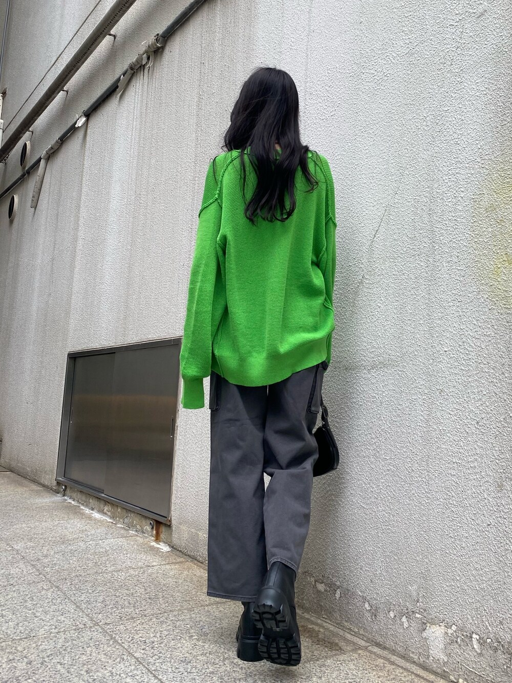 グリーン系のカーディガン/ボレロ、ホワイト系のキャミソール、ブラック系のデニムパンツを着用したレディースの春コーディネートの5枚目の写真