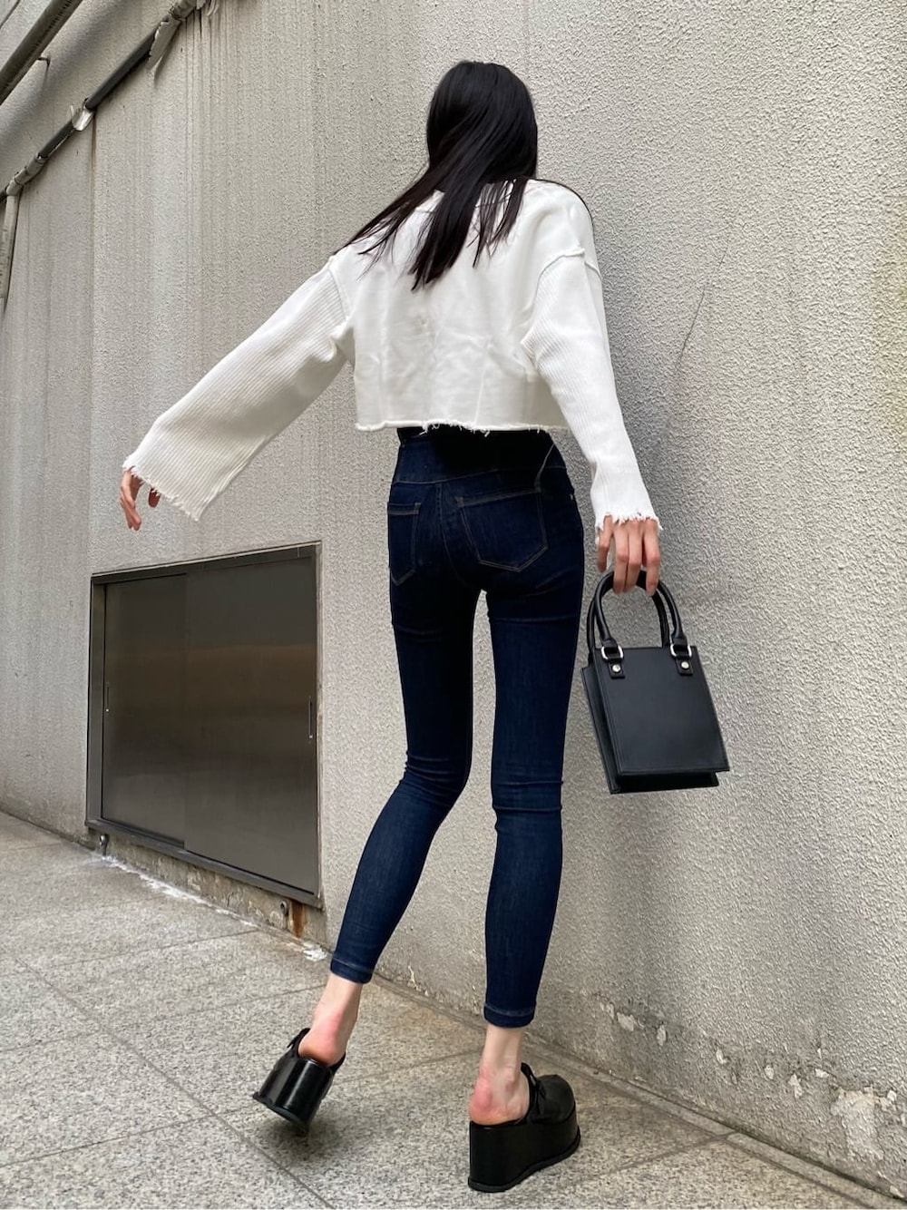 ブルー系のデニムパンツ、ブラック系のスリッポン、ブラック系のTシャツ/カットソーを着用したレディースの秋コーディネートの2枚目の写真