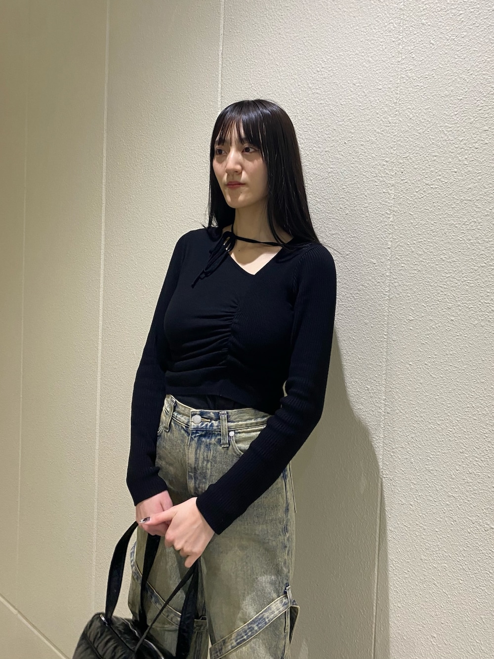 ブルー系のデニムパンツ、ブラック系のニット/セーター、ブラック系のボストンバッグを着用したレディースの冬コーディネートの6枚目の写真