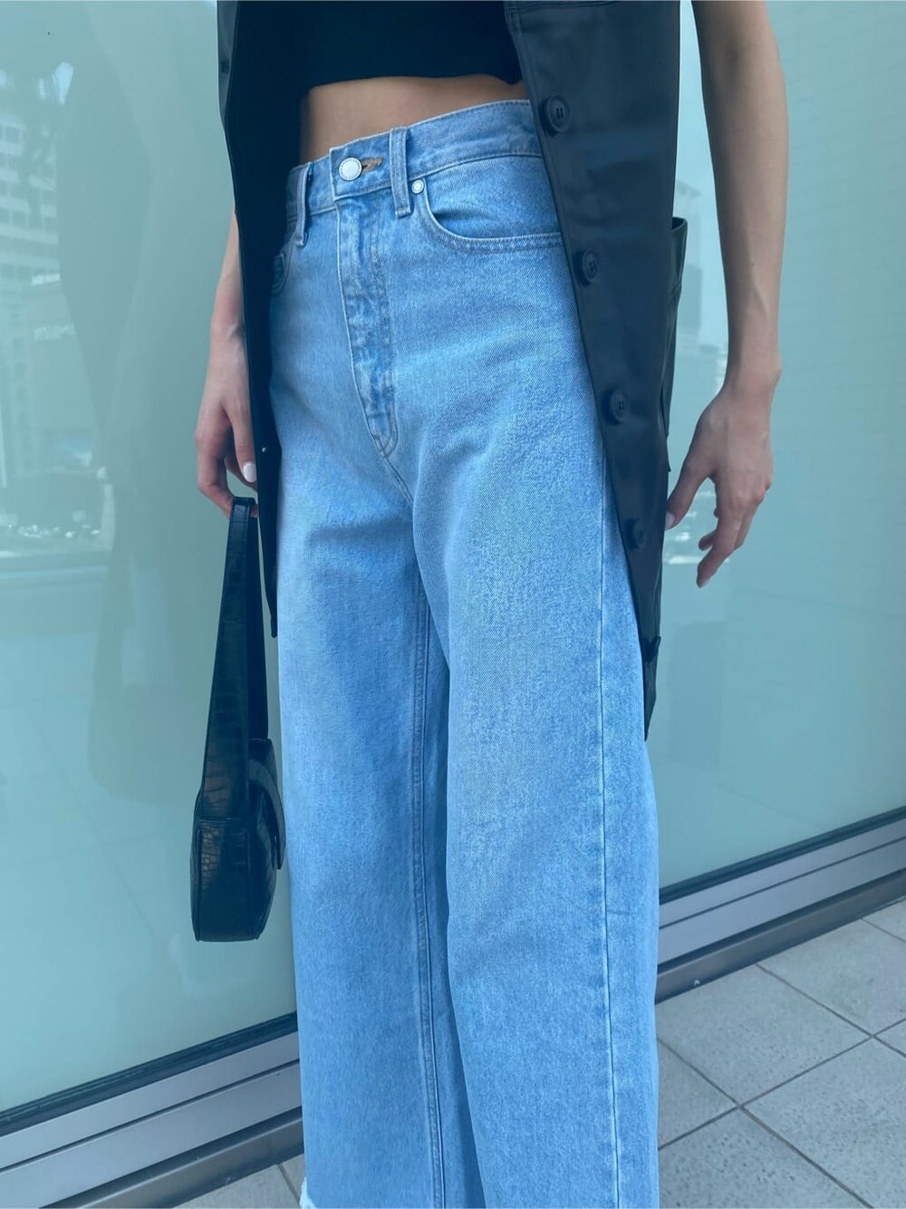 ブルー系のデニムパンツ、ブラック系のワンピース、ベージュ系のスリッポンを着用したレディースの夏コーディネートの8枚目の写真