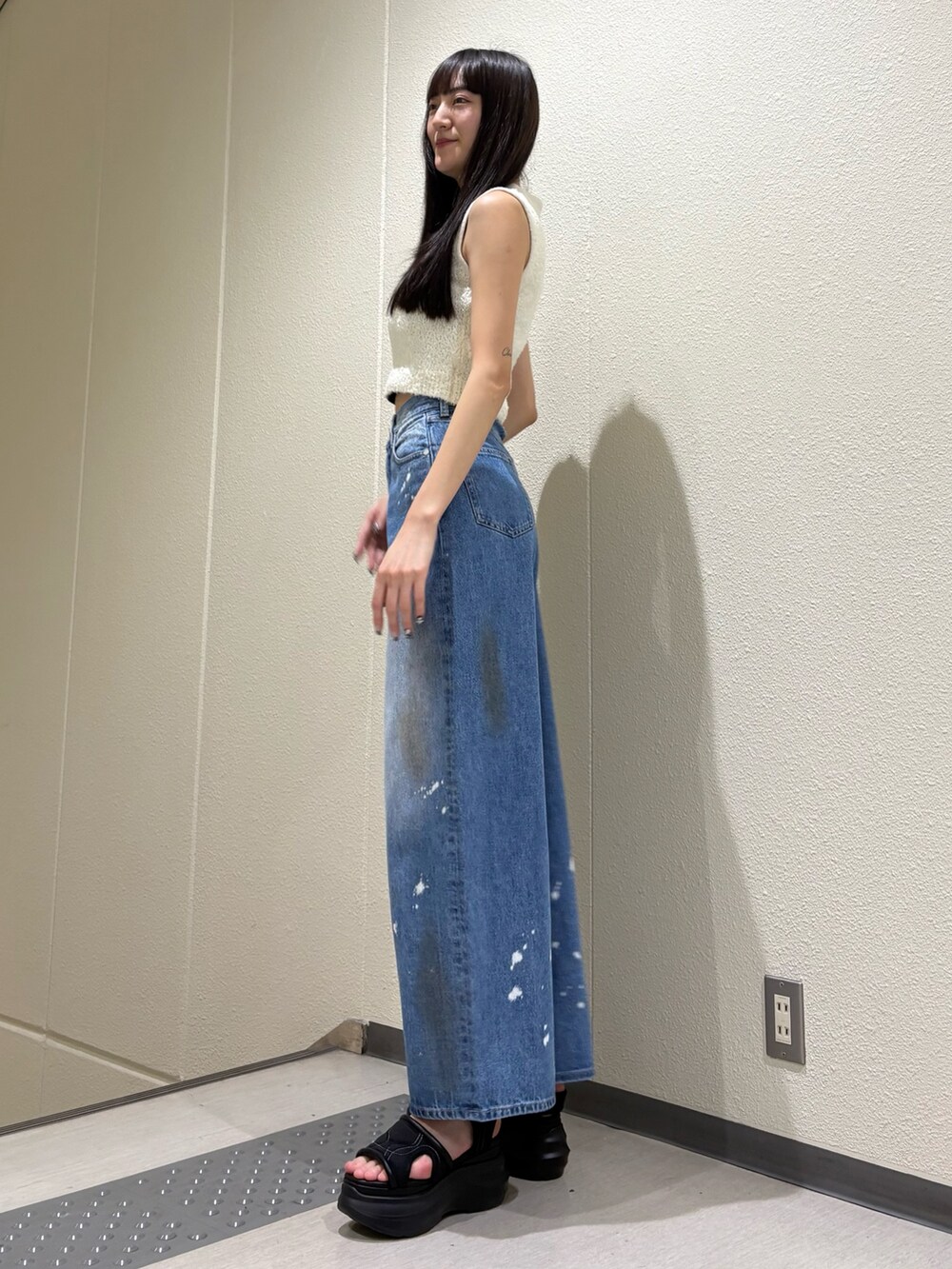 ブルー系のデニムパンツ、ホワイト系のニット/セーター、ブラック系のサンダルを着用したレディースの夏コーディネートの2枚目の写真