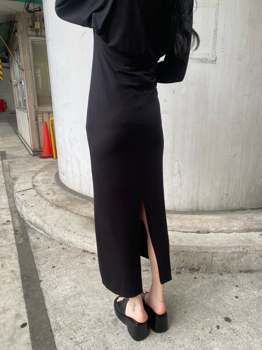 ブラック系のワンピース、ブラック系のサンダル、ホワイト系のハットを着用したレディースの春コーディネートの5枚目の写真