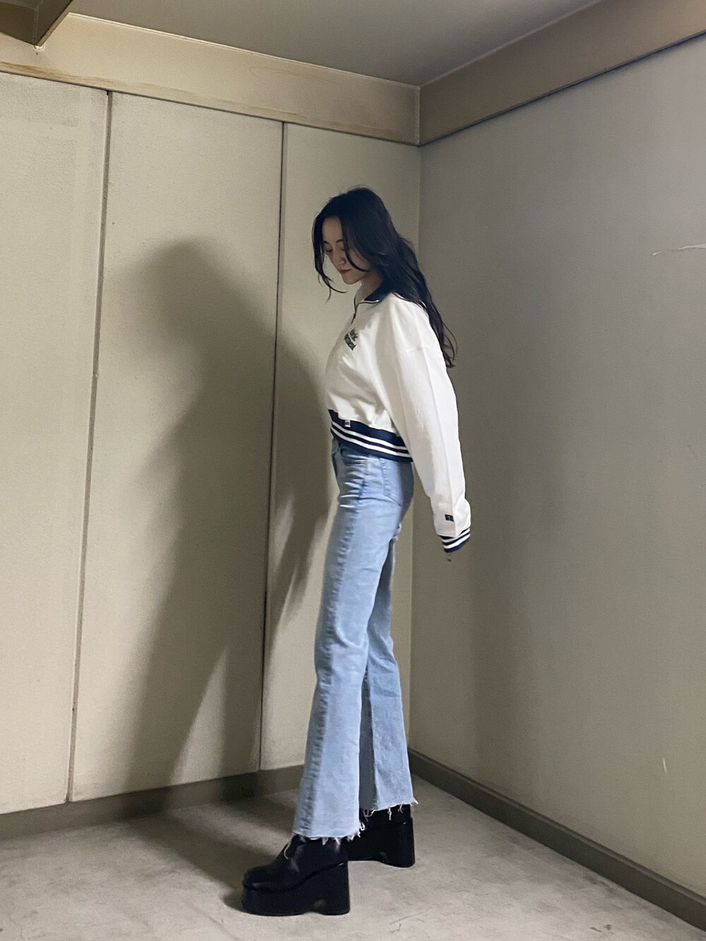 ホワイト系のTシャツ/カットソー、ブルー系のデニムパンツ、ブラック系のブーツを着用したレディースの春コーディネートの3枚目の写真