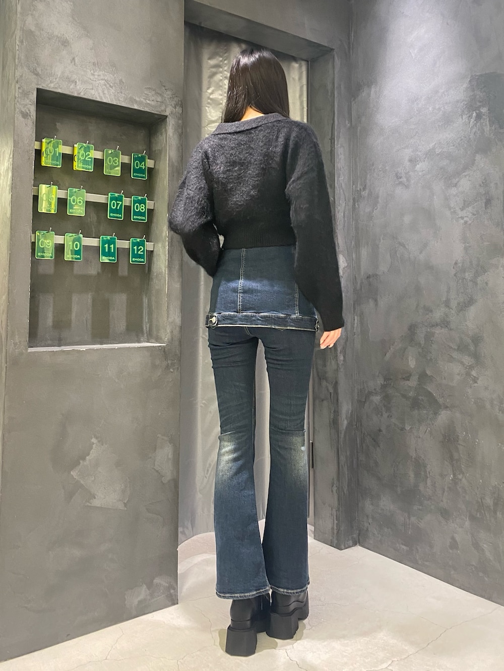 ブルー系のデニムパンツ、ブラック系のニット/セーター、ブラック系のブーツを着用したレディースの秋コーディネートの3枚目の写真