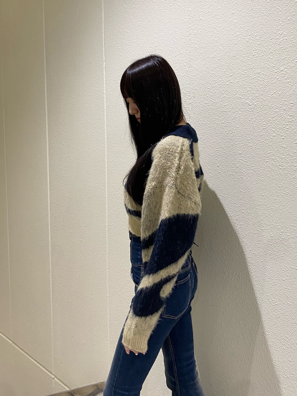 ブルー系のデニムパンツ、ブルー系のニット/セーター、ブラック系のブーツを着用したレディースの秋コーディネートの6枚目の写真