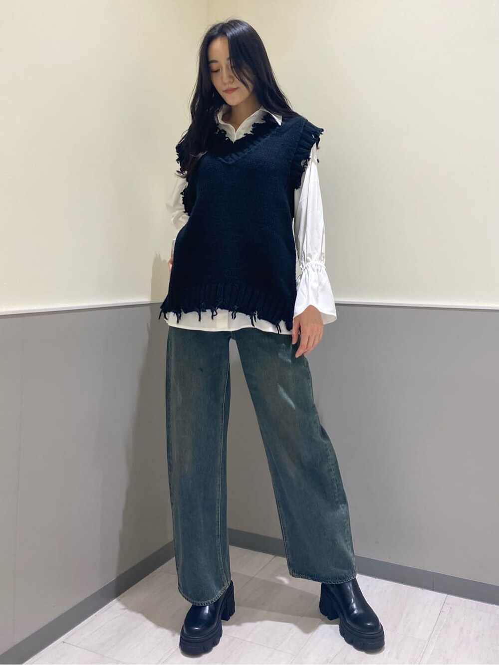 ブラック系のブーツ、ホワイト系のシャツ/ブラウス、ブルー系のデニムパンツを着用したレディースの秋コーディネートの2枚目の写真