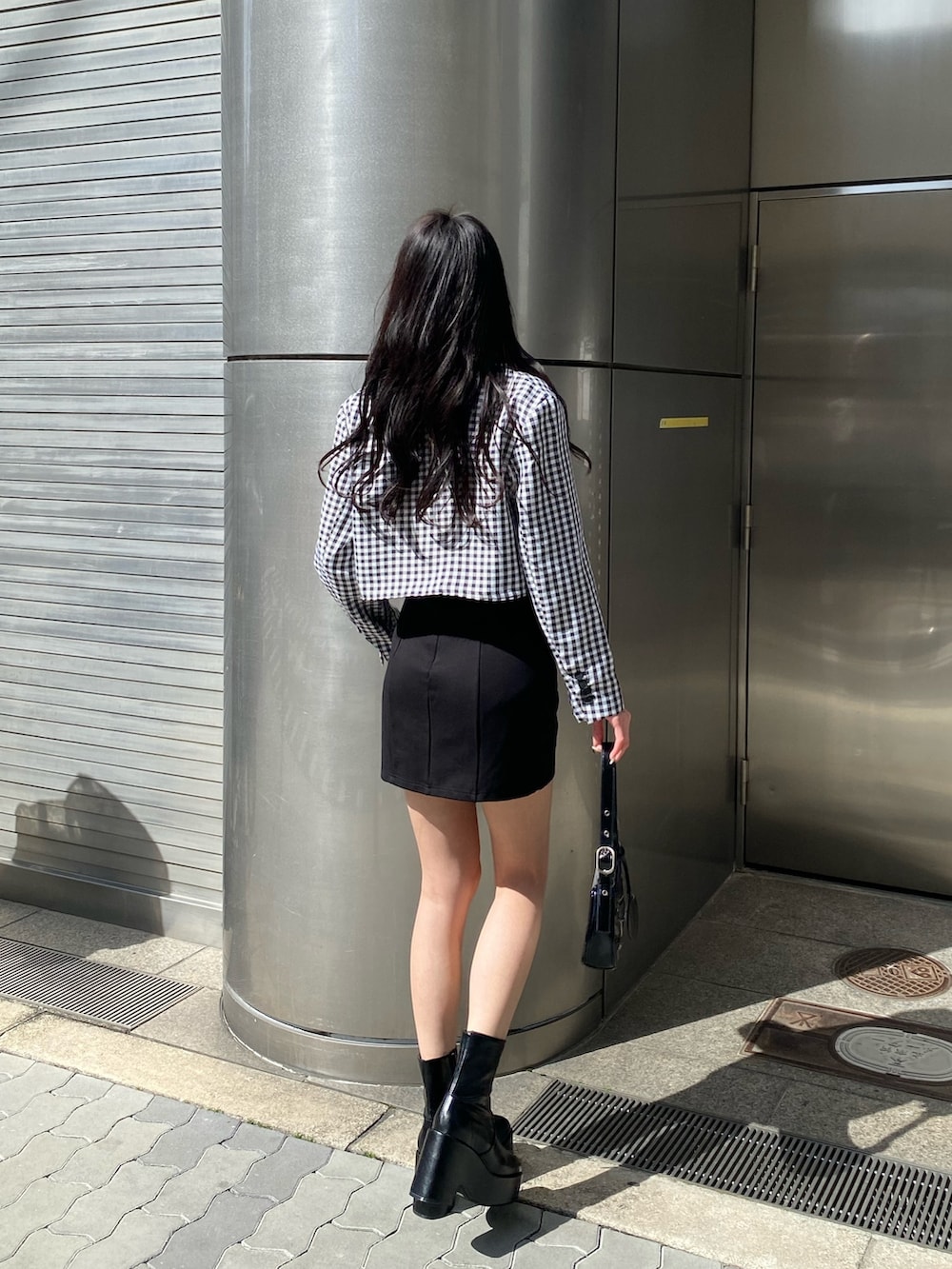 ブラック系のブーツ、ブラック系のスカート、ブラック系のハンドバッグを着用したレディースの春コーディネートの4枚目の写真