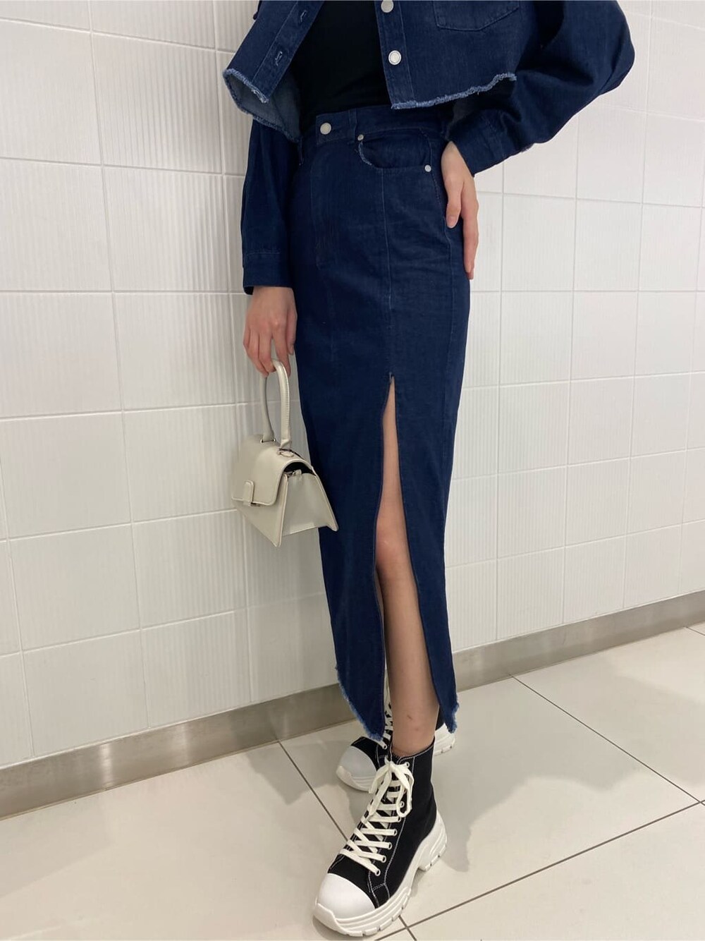 ブルー系のデニムジャケット、ブルー系のスカート、ホワイト系のハンドバッグを着用したレディースの夏コーディネートの8枚目の写真