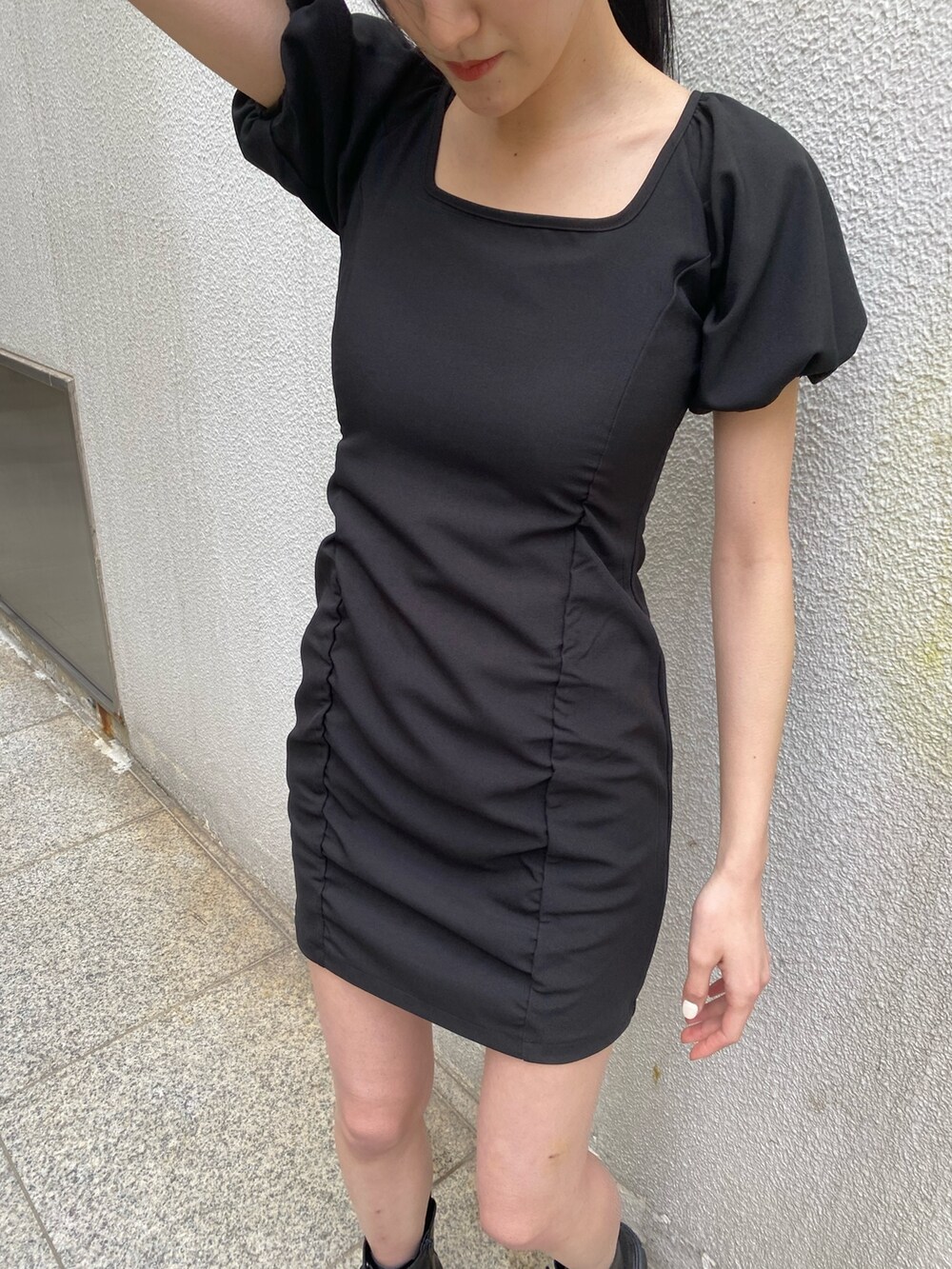 ブラック系のワンピース、ブラック系のブーツ、その他のハンドバッグを着用したレディースの春コーディネートの5枚目の写真