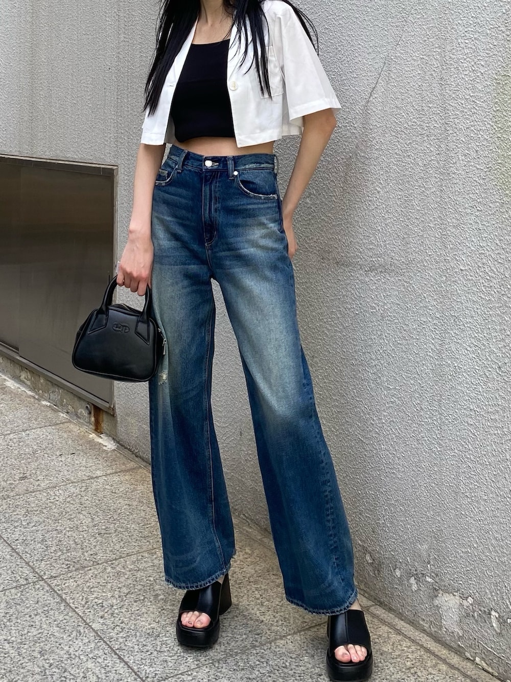 ブルー系のデニムパンツ、ブラック系のニット/セーター、ホワイト系のシャツ/ブラウスを着用したレディースの春コーディネートの5枚目の写真