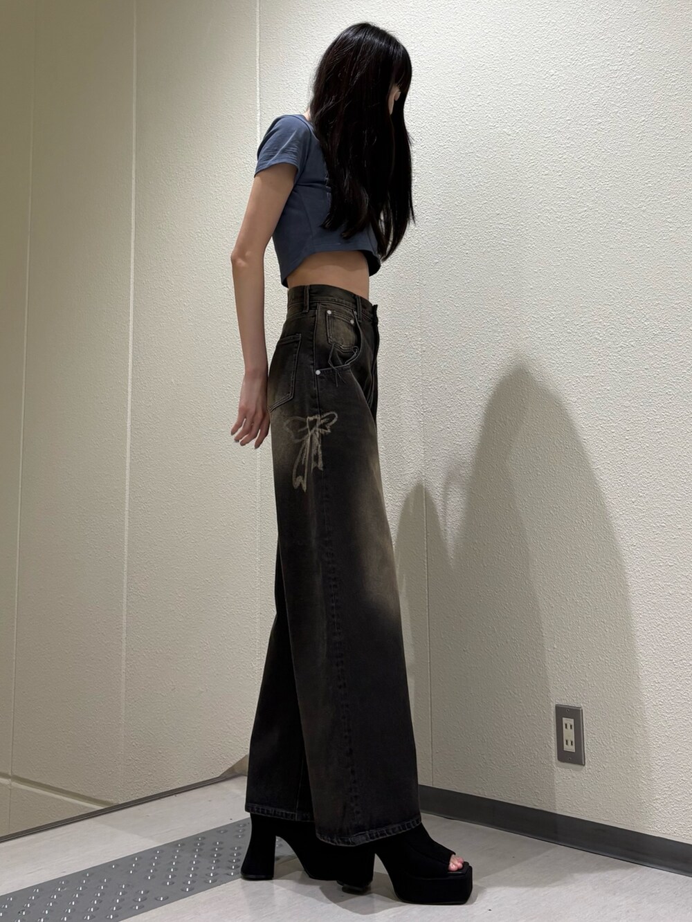 ブラック系のデニムパンツ、ブルー系のTシャツ/カットソー、ブラック系のサンダルを着用したレディースの夏コーディネートの4枚目の写真