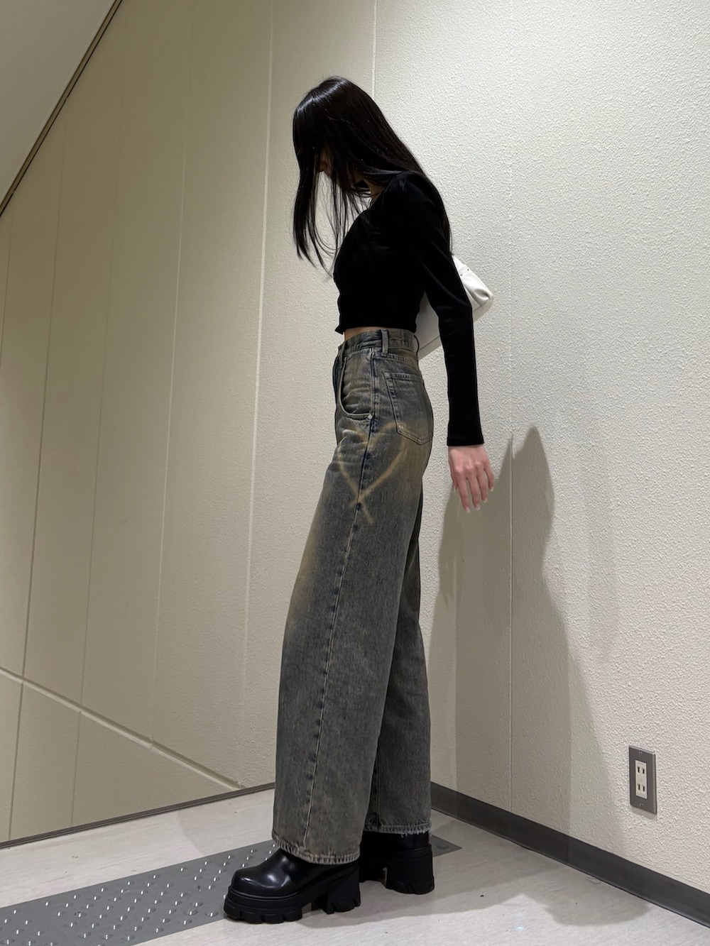 ブラック系のブーツ、ブルー系のデニムパンツ、ホワイト系のハンドバッグを着用したレディースの春コーディネートの5枚目の写真