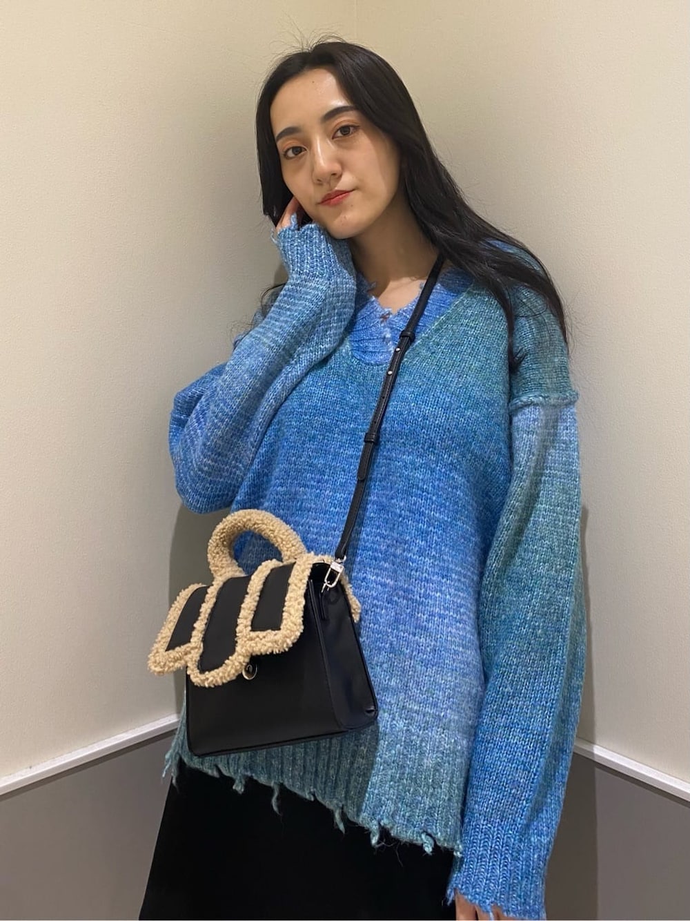 ブラック系のブーツ、ブラック系のスカート、ブルー系のニット/セーターを着用したレディースの秋コーディネートの5枚目の写真