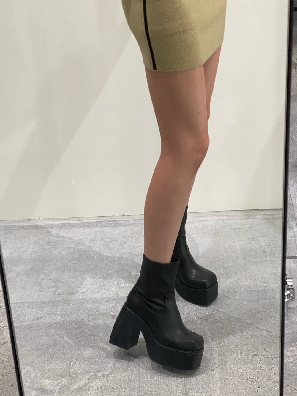 ベージュ系のニット/セーター、ベージュ系のスカート、ブラック系のブーツを着用したレディースの秋コーディネートの9枚目の写真