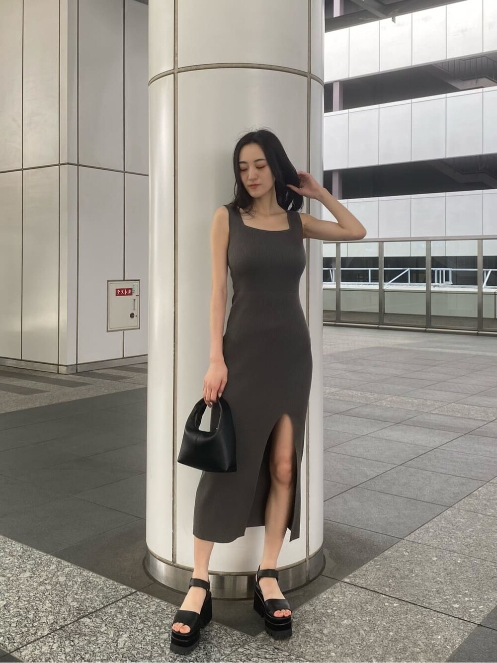 グレー系のワンピース、ブラック系のサンダル、ブラック系のハンドバッグを着用したレディースの夏コーディネートの2枚目の写真