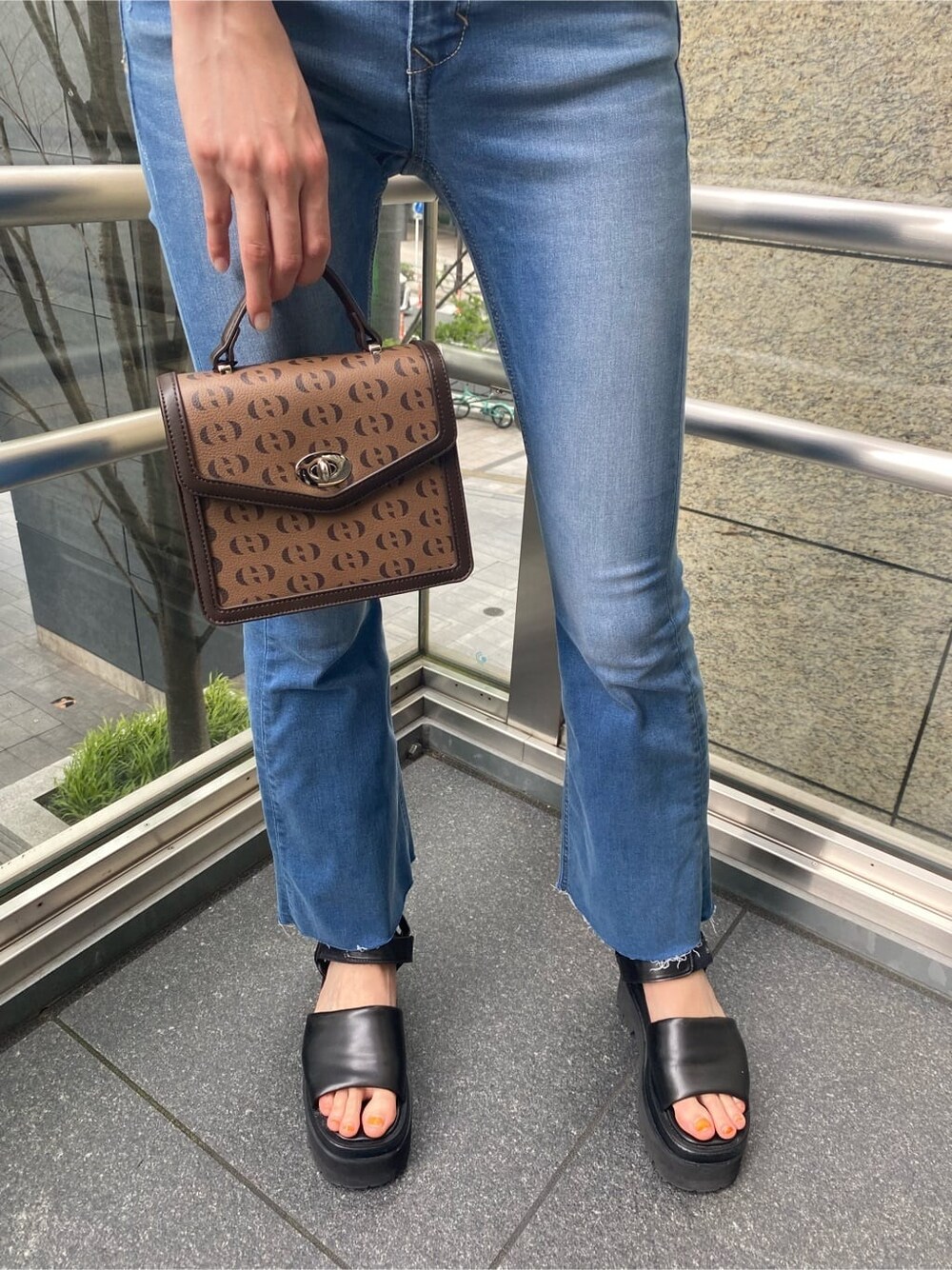 ブラック系のサンダル、その他のハンドバッグ、ブルー系のデニムパンツを着用したレディースの夏コーディネートの4枚目の写真