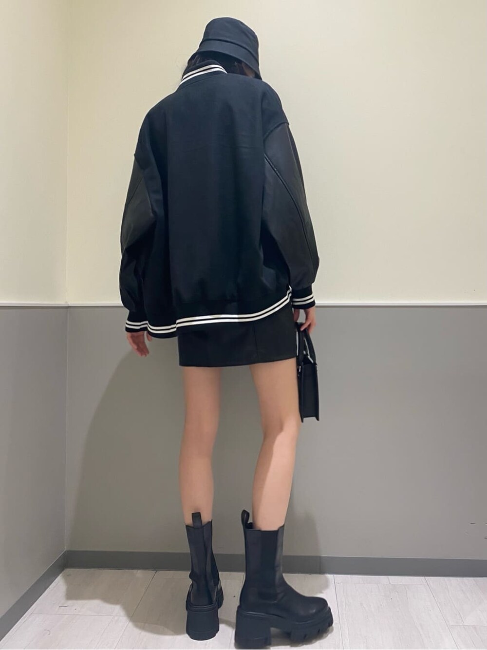 ブラック系のブーツ、ブラック系のハンドバッグ、ホワイト系のニット/セーターを着用したレディースの秋コーディネートの2枚目の写真