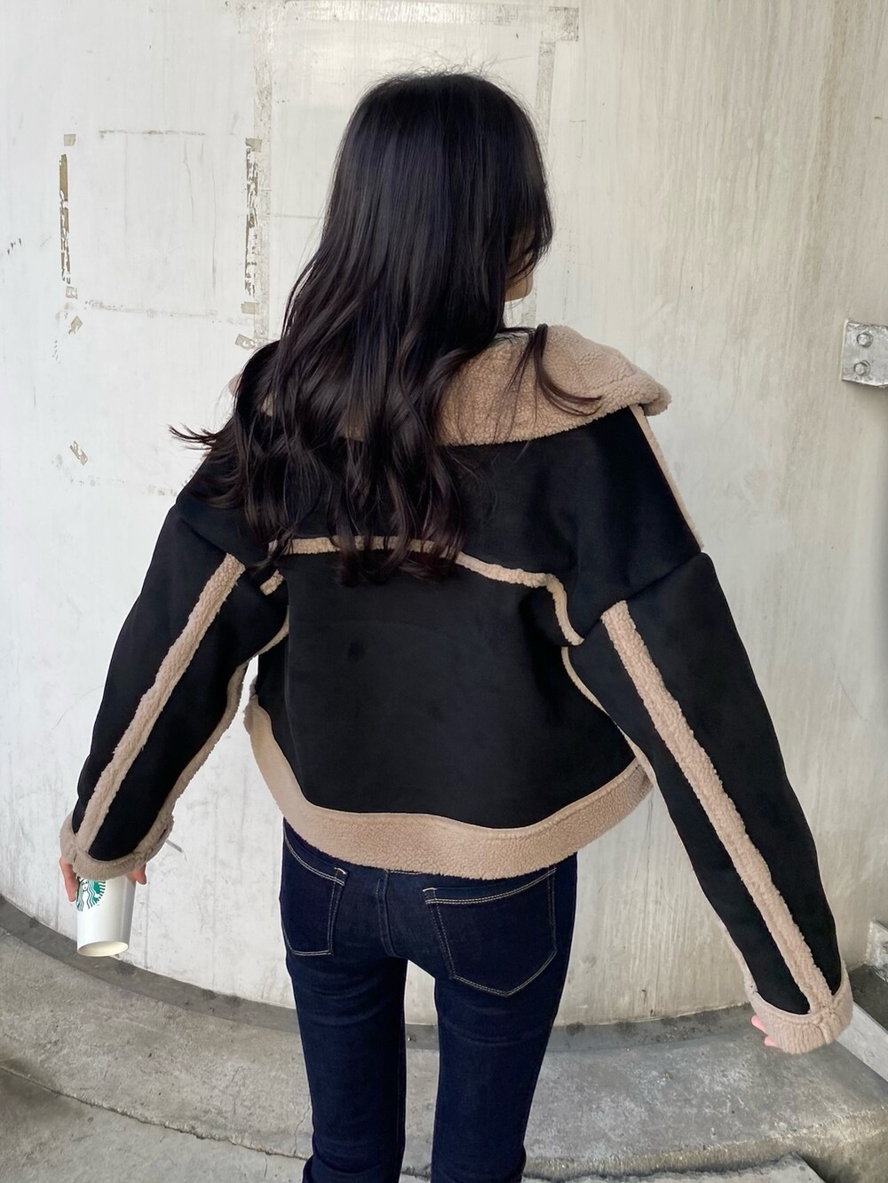 ブルー系のデニムパンツ、ブラック系のムートンコート、ホワイト系のニット/セーターを着用したレディースの秋コーディネートの5枚目の写真