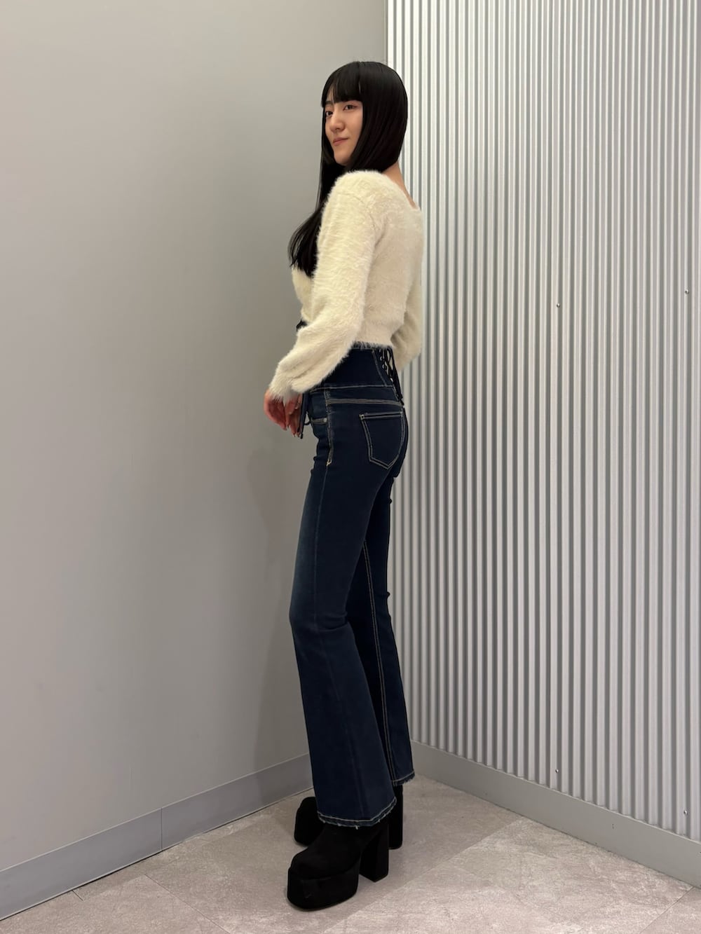 ブルー系のデニムパンツ、ブラック系のキャミソール、ホワイト系のニット/セーターを着用したレディースの秋コーディネートの2枚目の写真