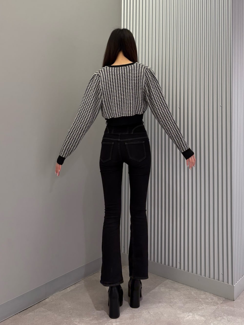 ブラック系のデニムパンツ、ブラック系のニット/セーター、ブラック系のブーツを着用したレディースの秋コーディネートの3枚目の写真