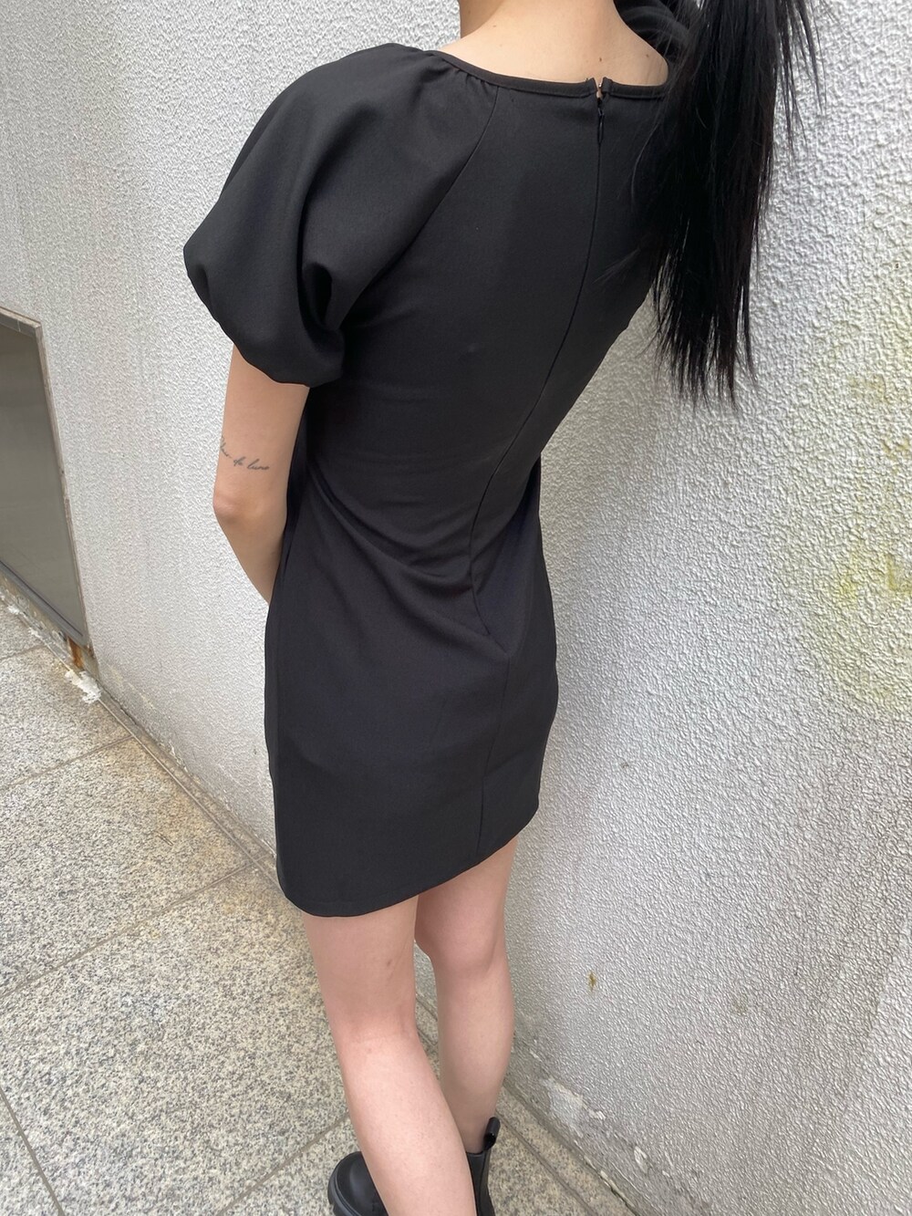 ブラック系のワンピース、ブラック系のブーツ、その他のハンドバッグを着用したレディースの春コーディネートの6枚目の写真