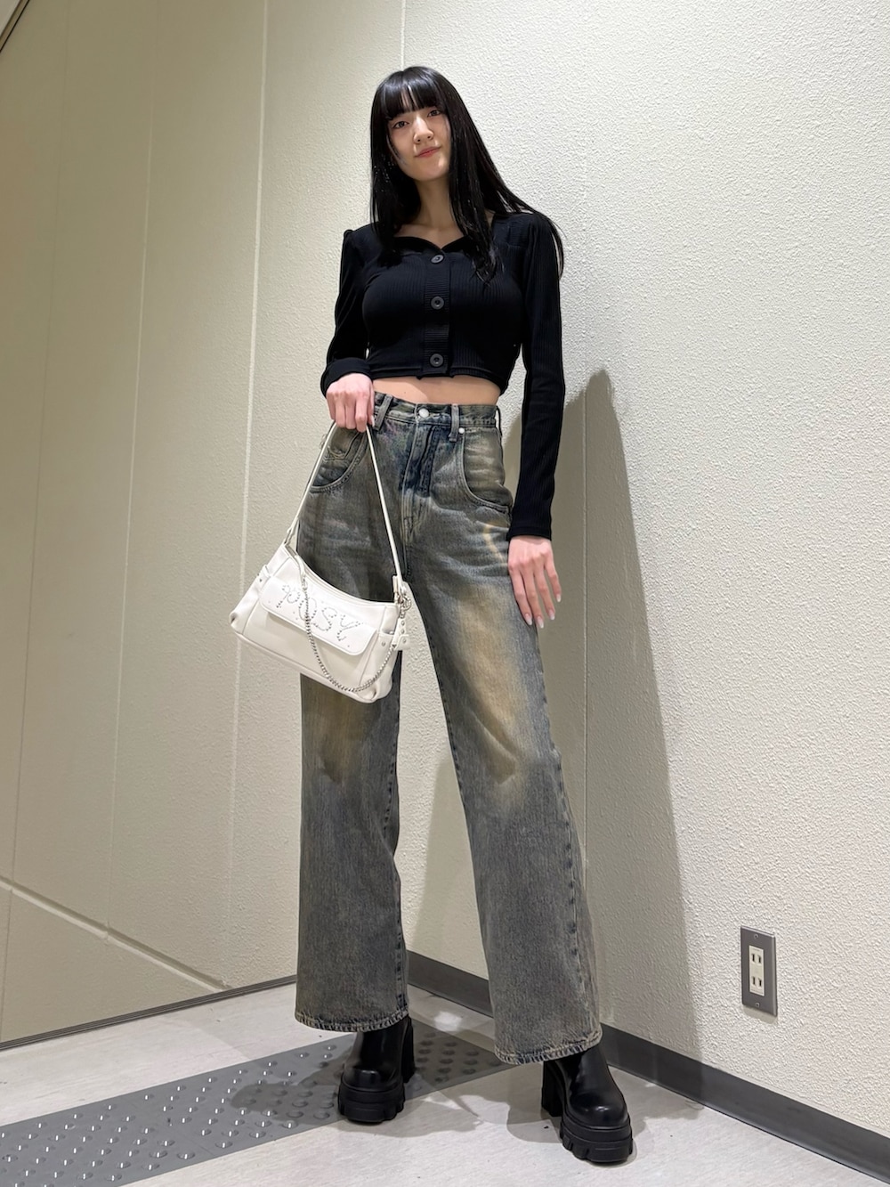 ブラック系のブーツ、ブルー系のデニムパンツ、ホワイト系のハンドバッグを着用したレディースの春コーディネートの2枚目の写真