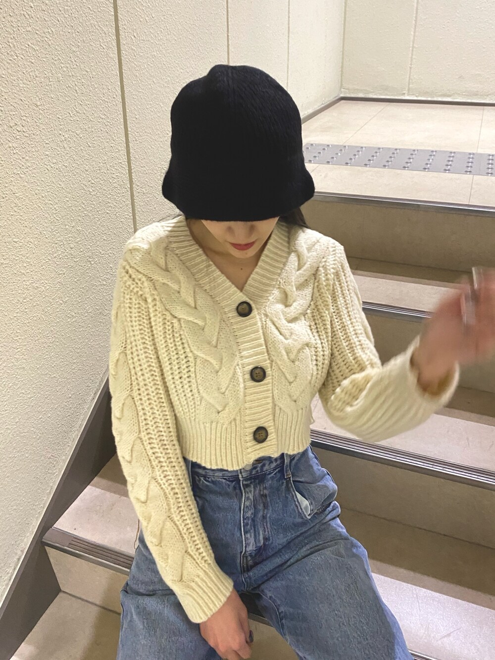 ブルー系のデニムパンツ、ホワイト系のカーディガン/ボレロ、ブラック系のハットを着用したレディースの秋コーディネートの4枚目の写真