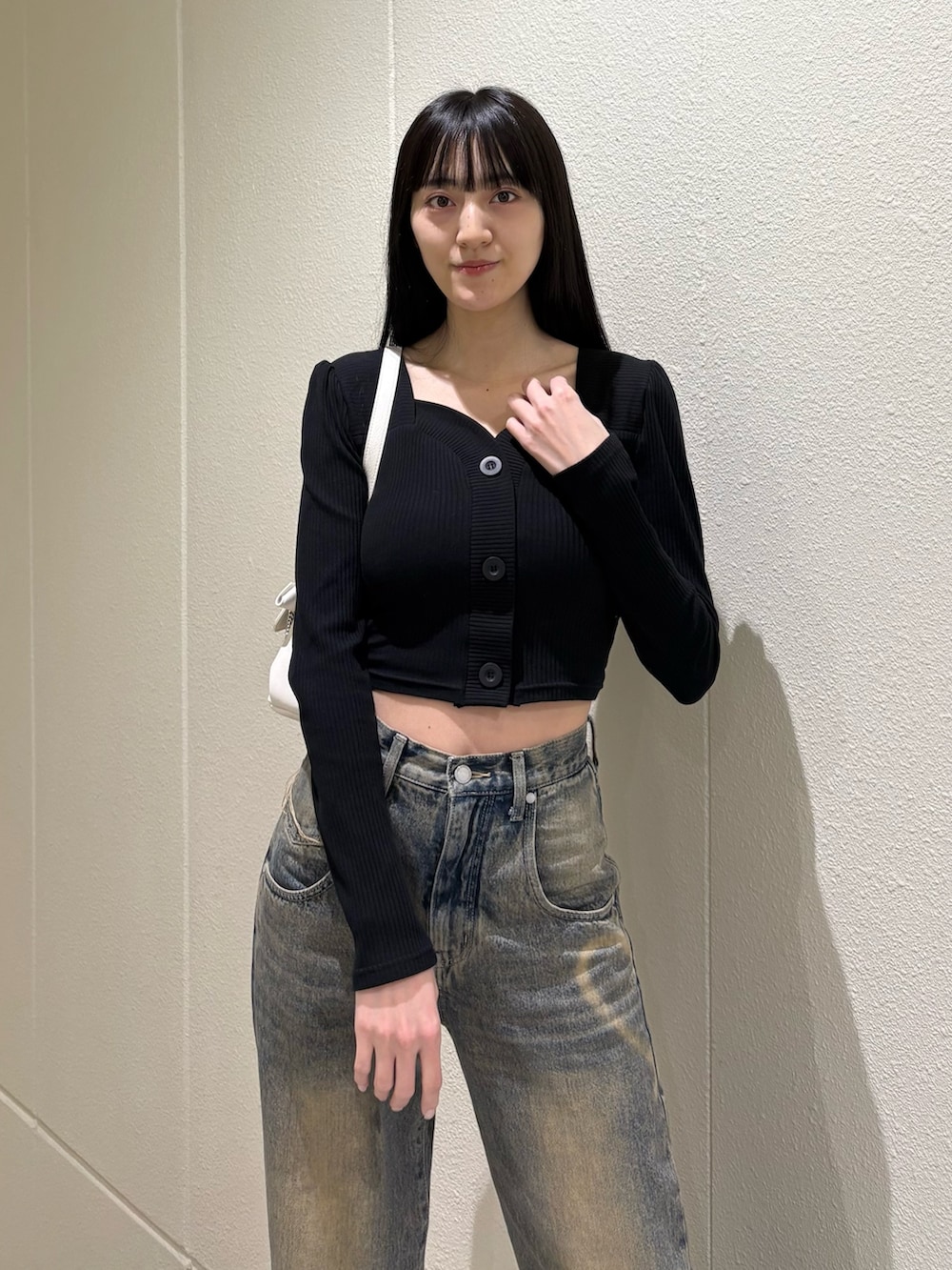 ブラック系のブーツ、ブルー系のデニムパンツ、ホワイト系のハンドバッグを着用したレディースの春コーディネートの7枚目の写真