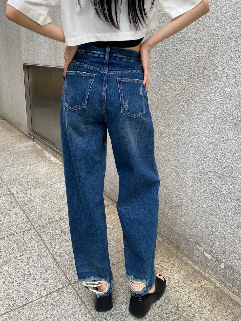 ブルー系のデニムパンツ、ブラック系のニット/セーター、ホワイト系のシャツ/ブラウスを着用したレディースの春コーディネートの9枚目の写真