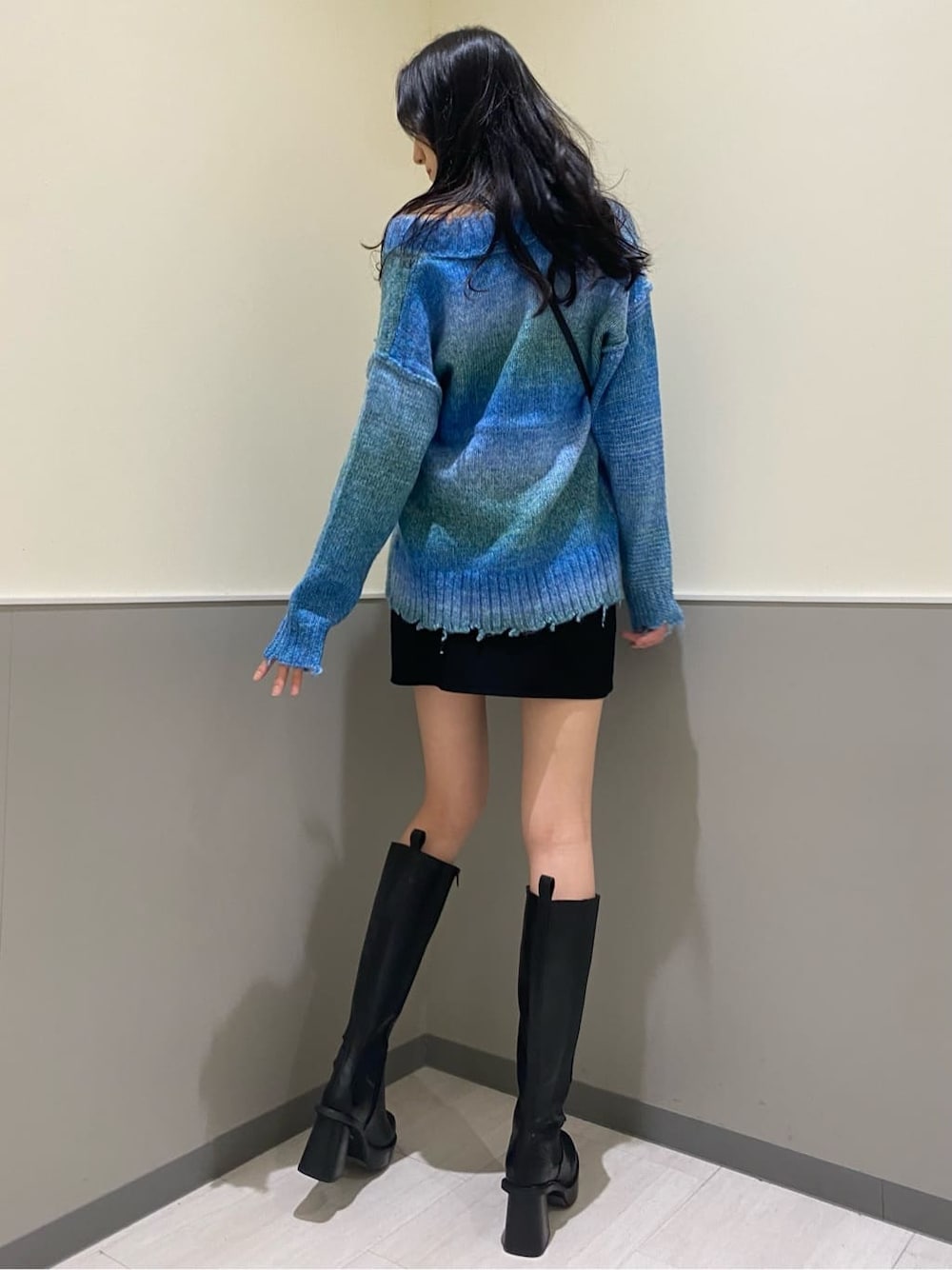 ブラック系のブーツ、ブラック系のスカート、ブルー系のニット/セーターを着用したレディースの秋コーディネートの3枚目の写真