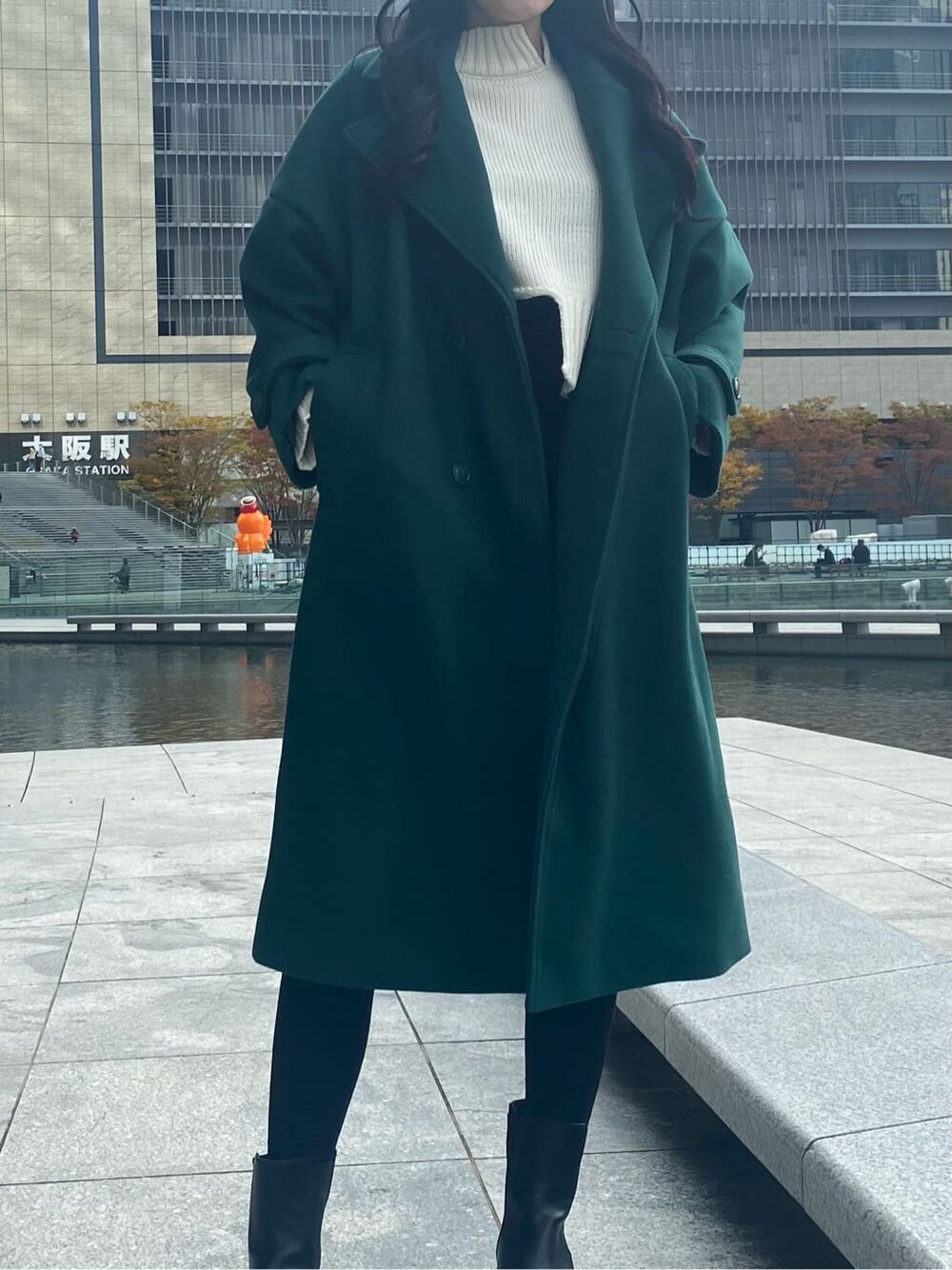 ブラック系のデニムパンツ、ホワイト系のニット/セーター、グリーン系のチェスターコートを着用したレディースの秋コーディネートの3枚目の写真