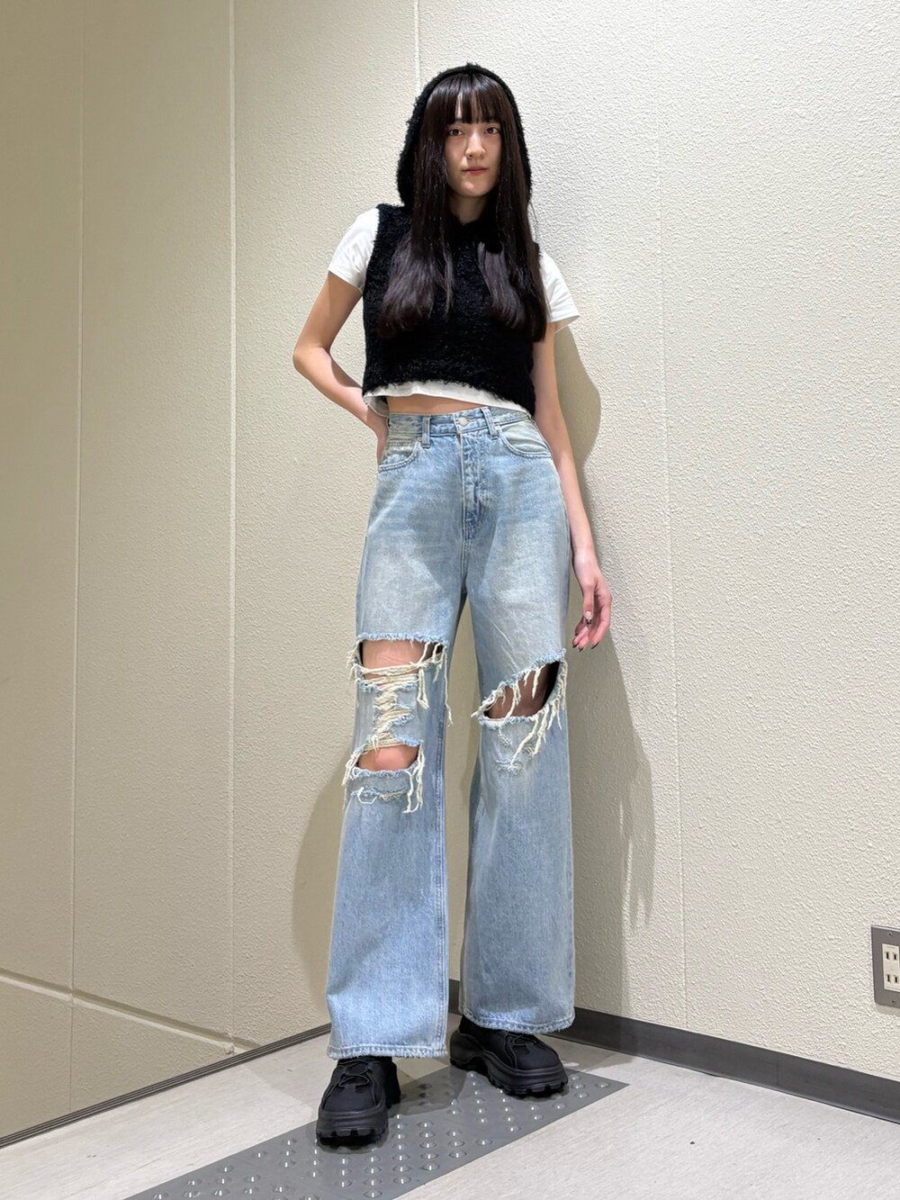 ホワイト系のTシャツ/カットソー、ブラック系のニット/セーター、ブルー系のデニムパンツを着用したレディースの春コーディネートの5枚目の写真