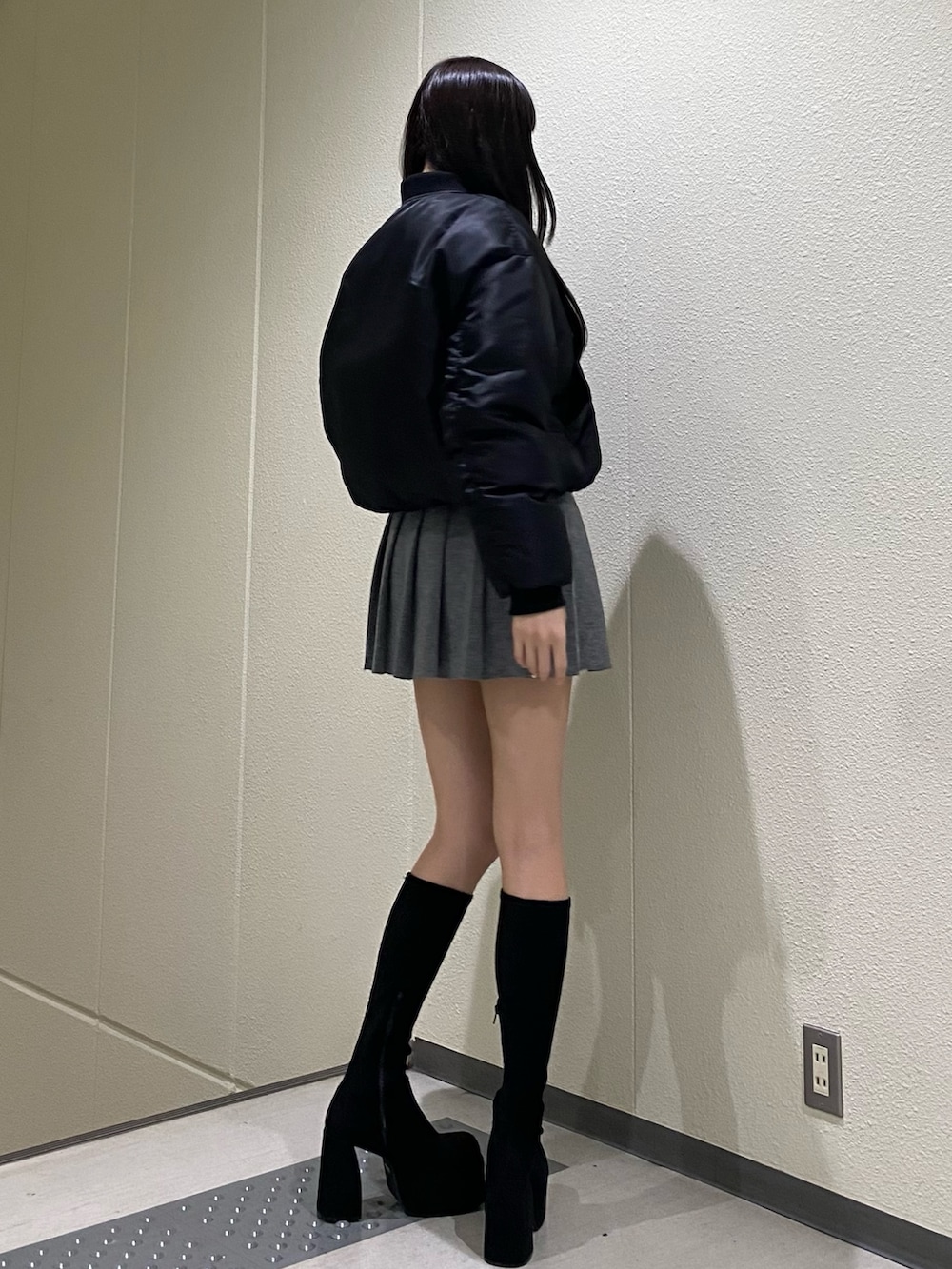 グレー系のスカート、ブラック系のブルゾン、その他のブーツを着用したレディースの秋コーディネートの4枚目の写真