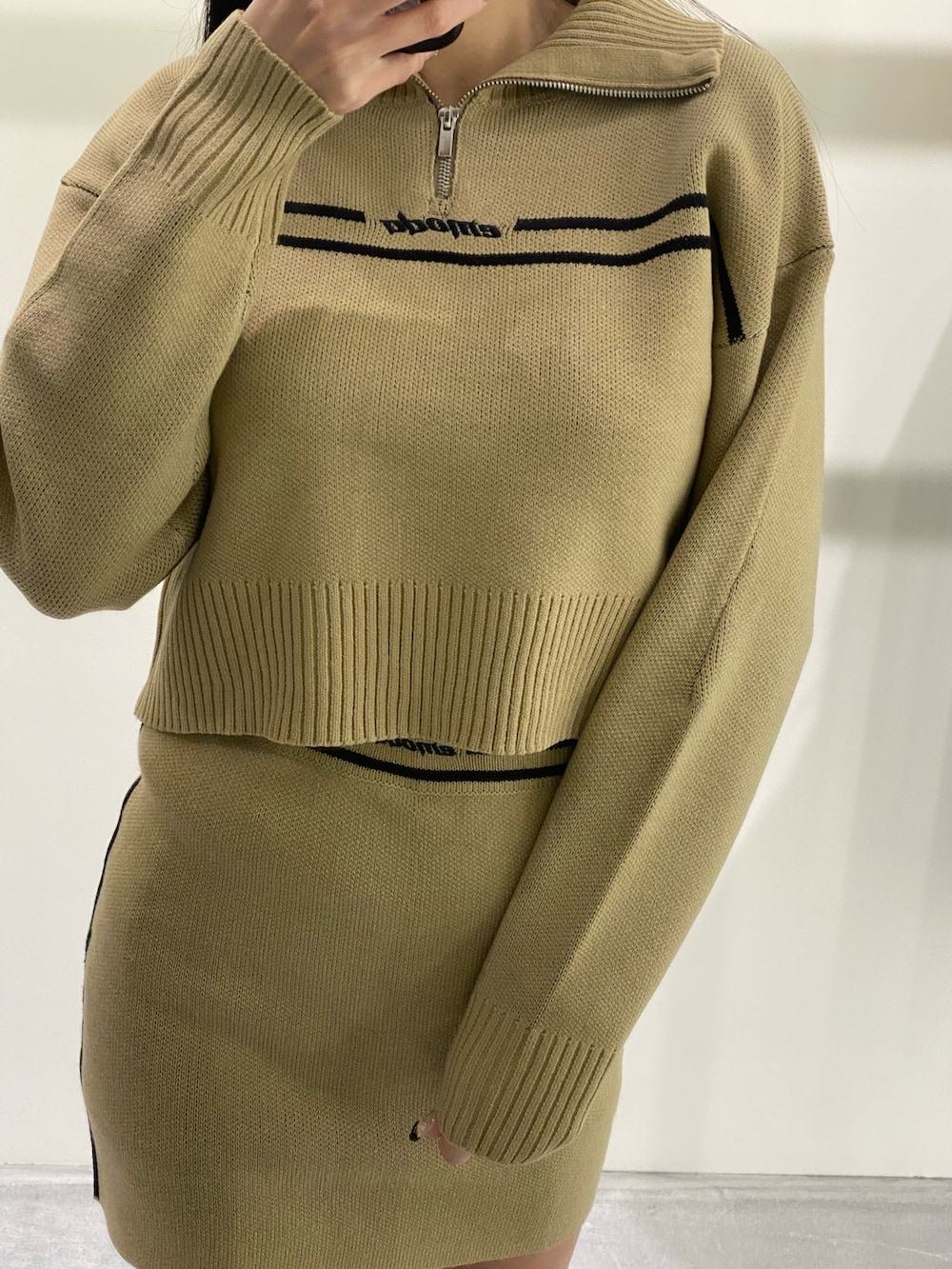 ベージュ系のニット/セーター、ベージュ系のスカート、ブラック系のブーツを着用したレディースの秋コーディネートの3枚目の写真