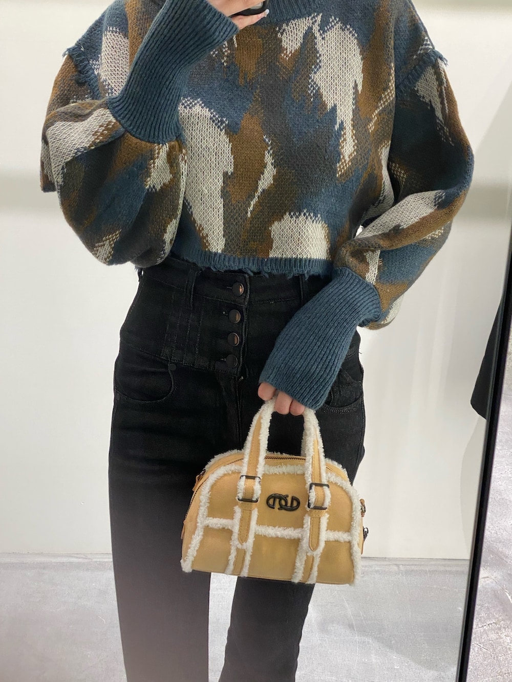 ベージュ系のハンドバッグ、ブラック系のデニムパンツ、ブルー系のニット/セーターを着用したレディースの秋コーディネートの4枚目の写真