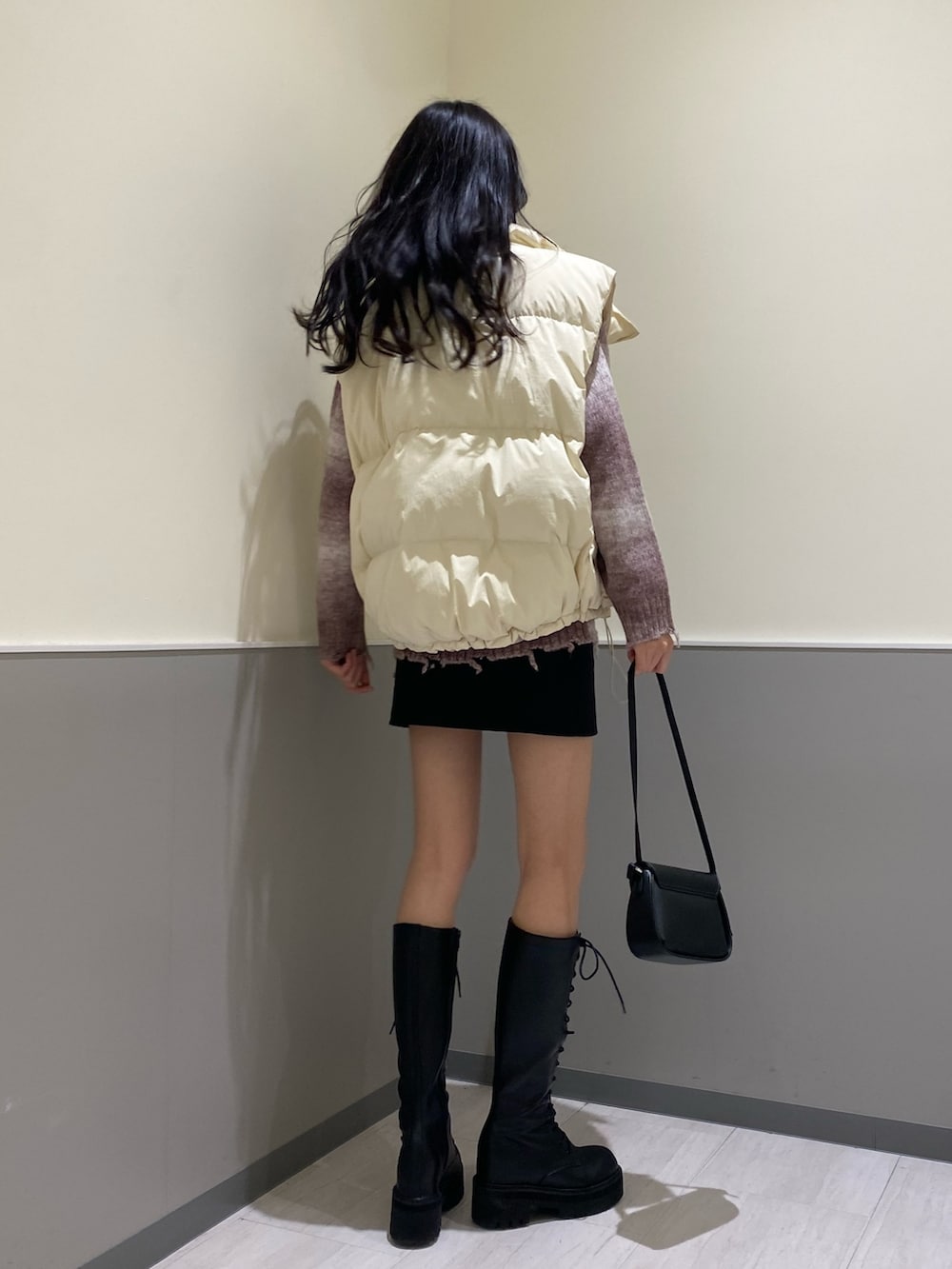 ブラック系のスカート、ピンク系のニット/セーター、ホワイト系のダウンベストを着用したレディースの秋コーディネートの3枚目の写真