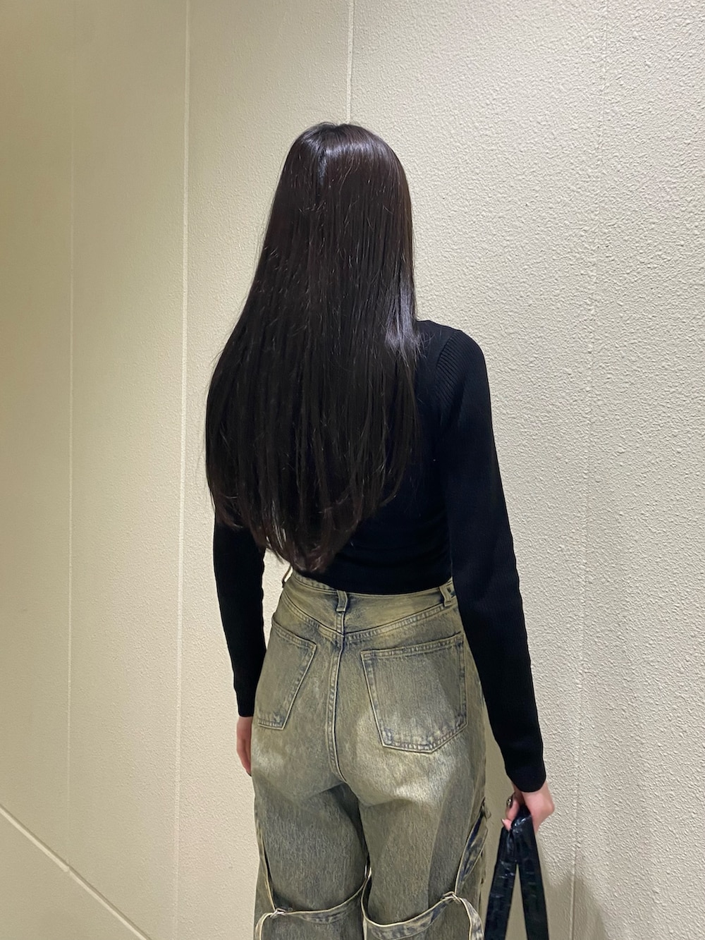 ブルー系のデニムパンツ、ブラック系のニット/セーター、ブラック系のボストンバッグを着用したレディースの冬コーディネートの7枚目の写真