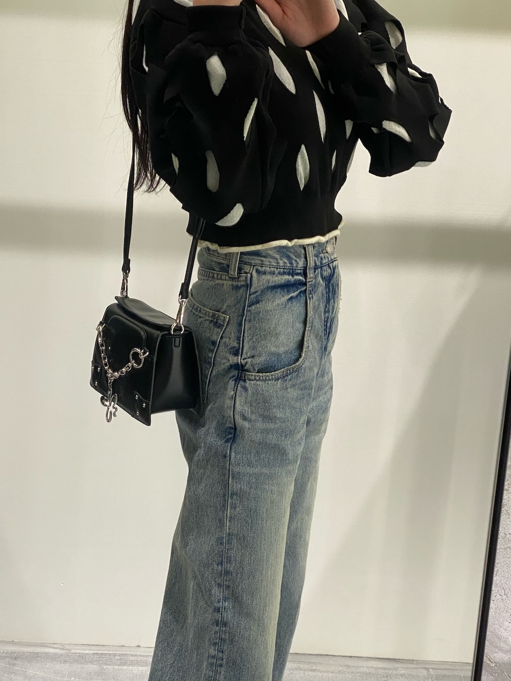 ブルー系のデニムパンツ、ブラック系のニット/セーター、ブラック系のショルダーバッグを着用したレディースの冬コーディネートの5枚目の写真