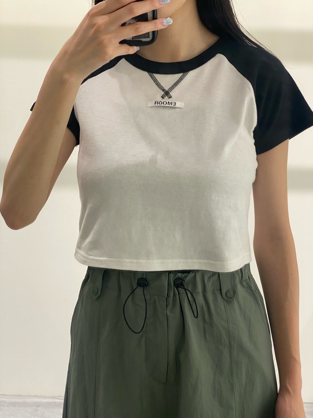 グリーン系のスカート、ブラック系のTシャツ/カットソー、ブラック系のサンダルを着用したレディースの夏コーディネートの5枚目の写真