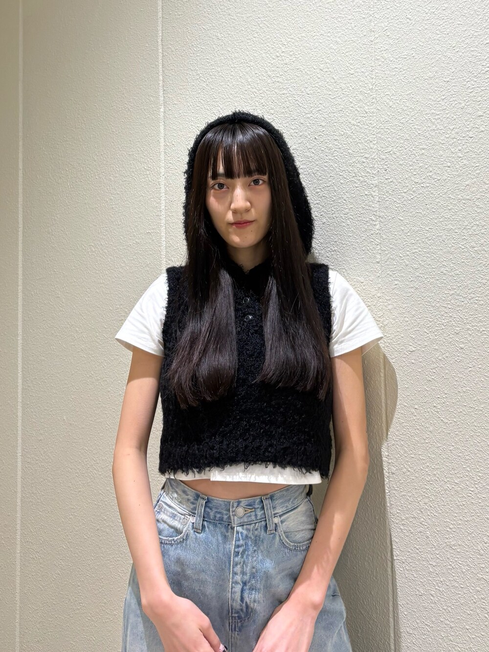 ホワイト系のTシャツ/カットソー、ブラック系のニット/セーター、ブルー系のデニムパンツを着用したレディースの春コーディネートの6枚目の写真