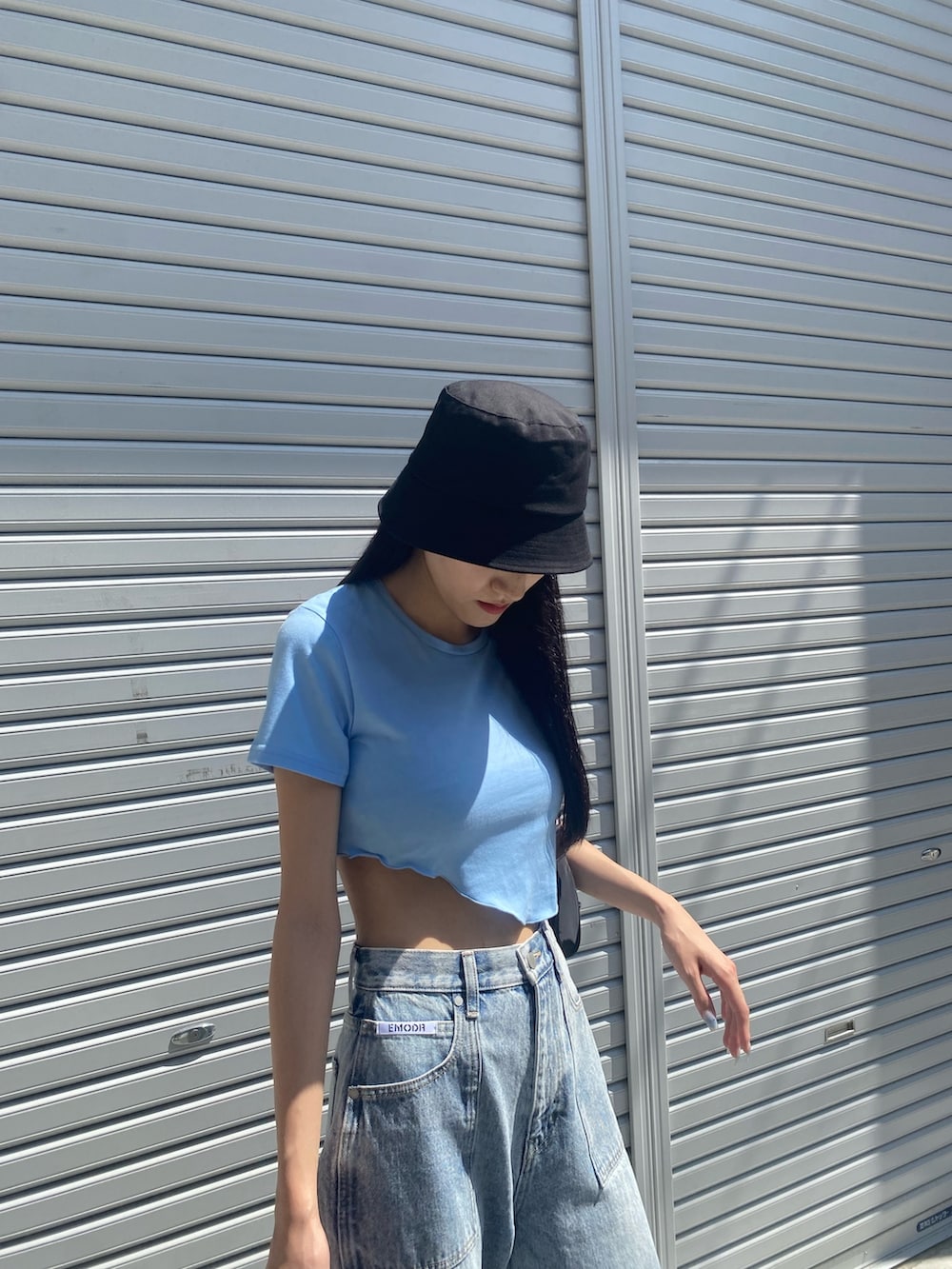 ブルー系のデニムパンツ、ブラック系のサンダル、ブラック系のハンドバッグを着用したレディースの夏コーディネートの6枚目の写真