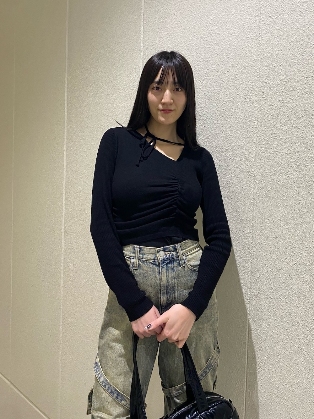 ブルー系のデニムパンツ、ブラック系のニット/セーター、ブラック系のボストンバッグを着用したレディースの冬コーディネートの5枚目の写真