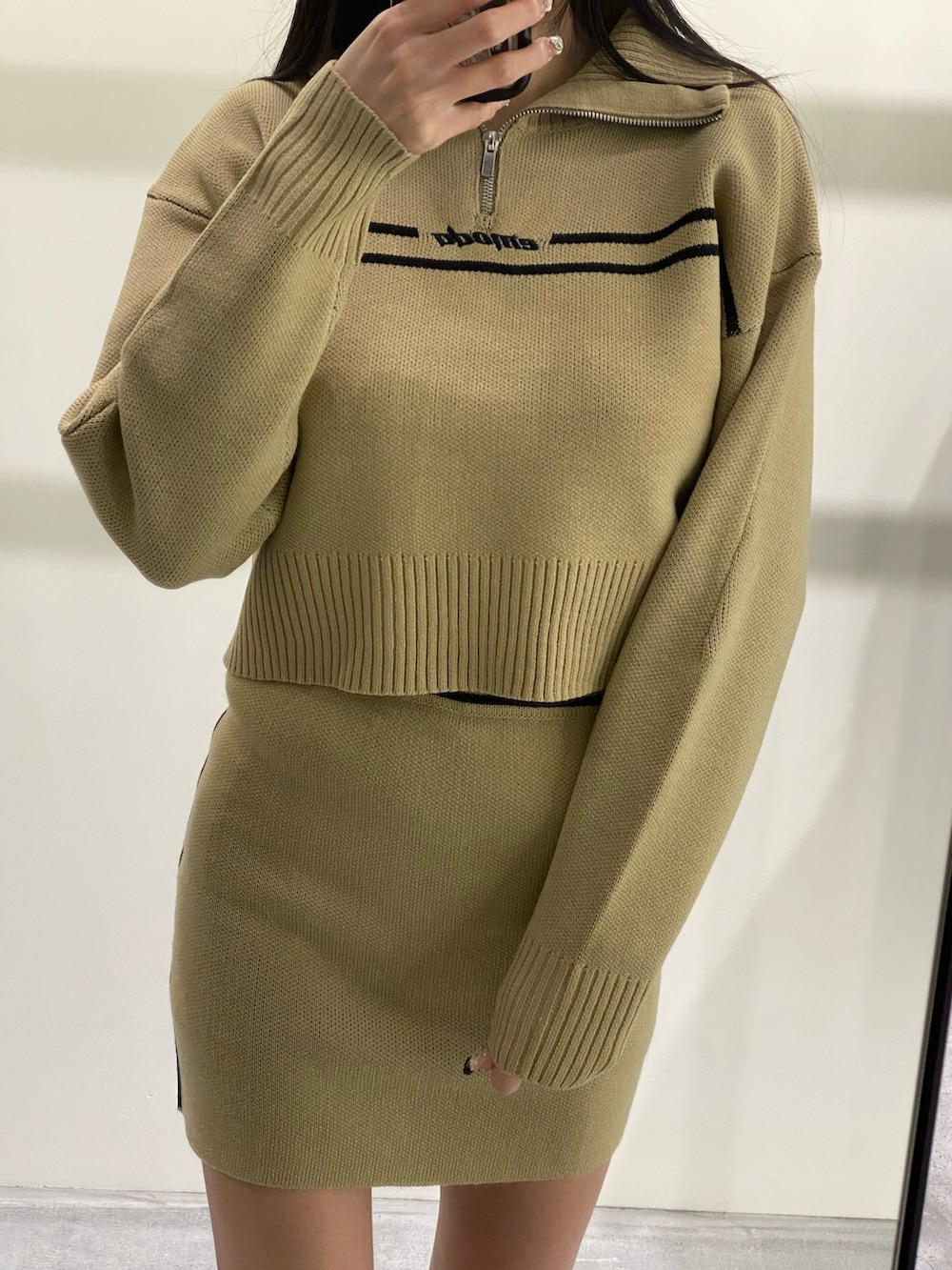 ベージュ系のニット/セーター、ベージュ系のスカート、ブラック系のブーツを着用したレディースの秋コーディネートの2枚目の写真