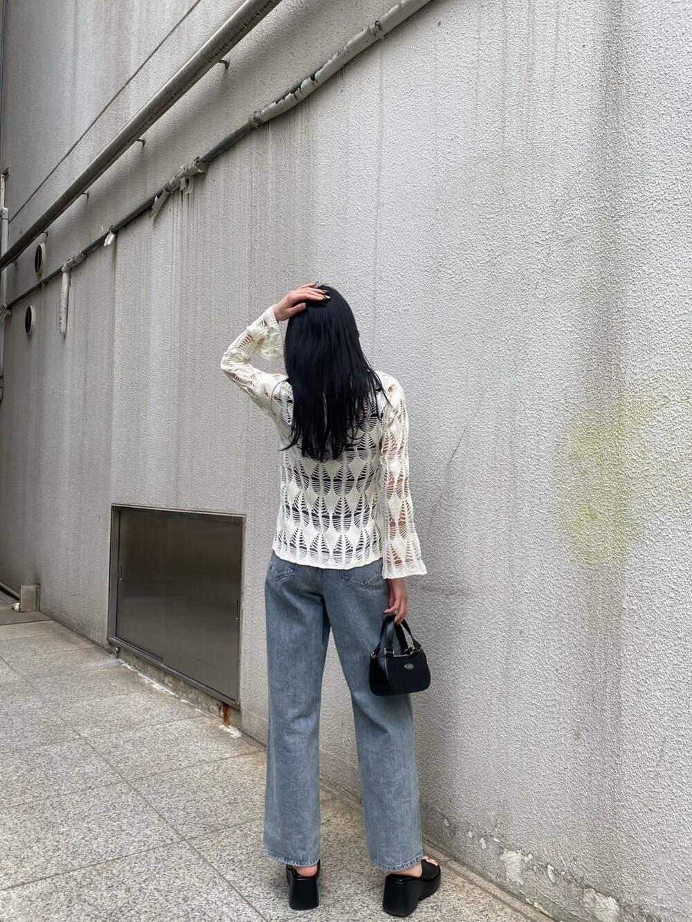 ブラック系のハンドバッグ、ブラック系のサンダル、ブルー系のデニムパンツを着用したレディースの春コーディネートの3枚目の写真