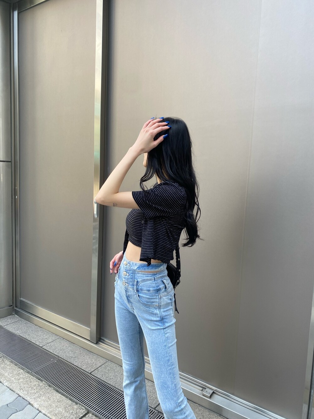 ブラック系のアンサンブル、ブルー系のデニムパンツ、ブラック系のサンダルを着用したレディースの春コーディネートの5枚目の写真